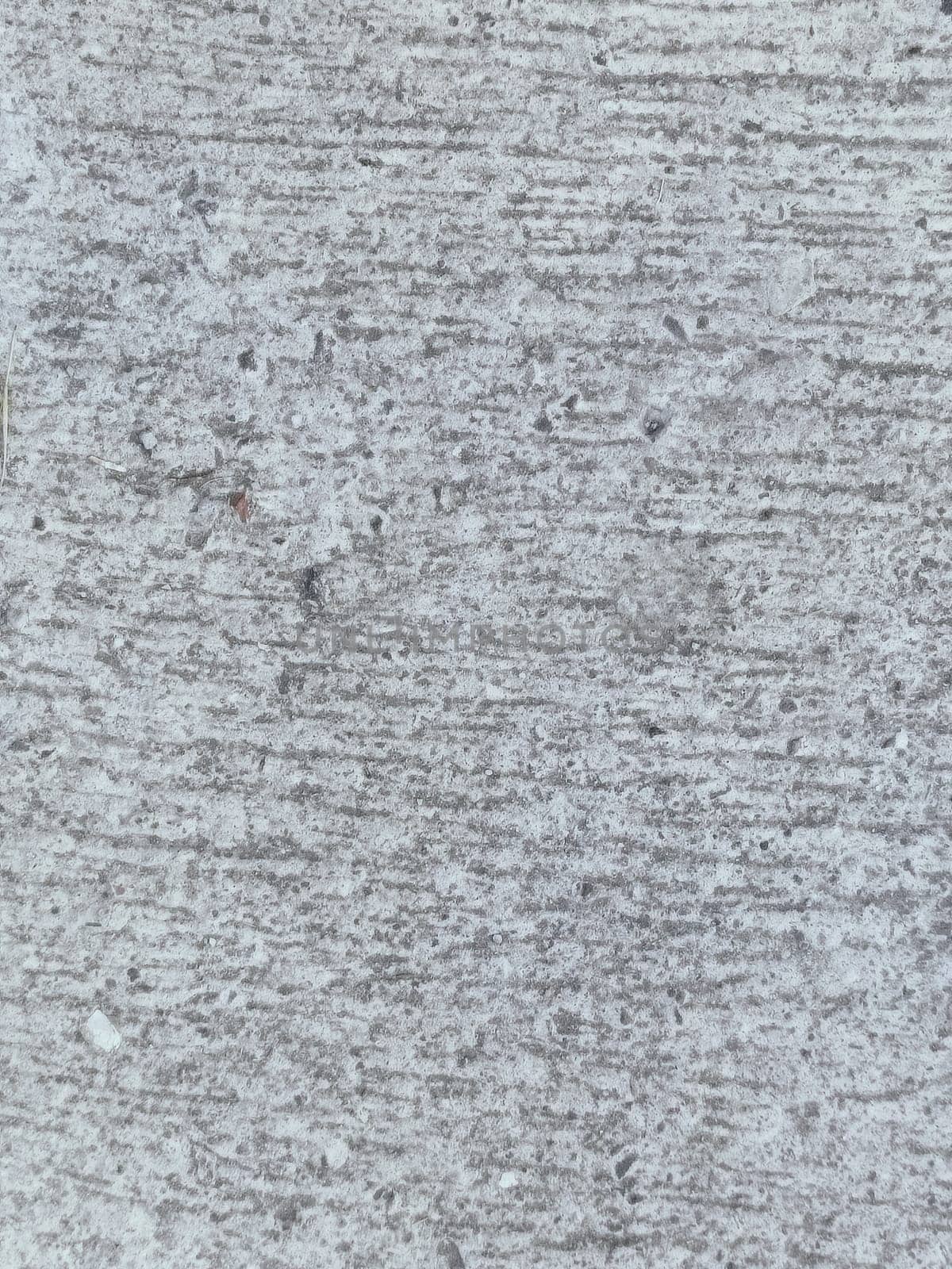 A grey and white wall with a few spots of color. The wall is made of concrete and has a rough texture