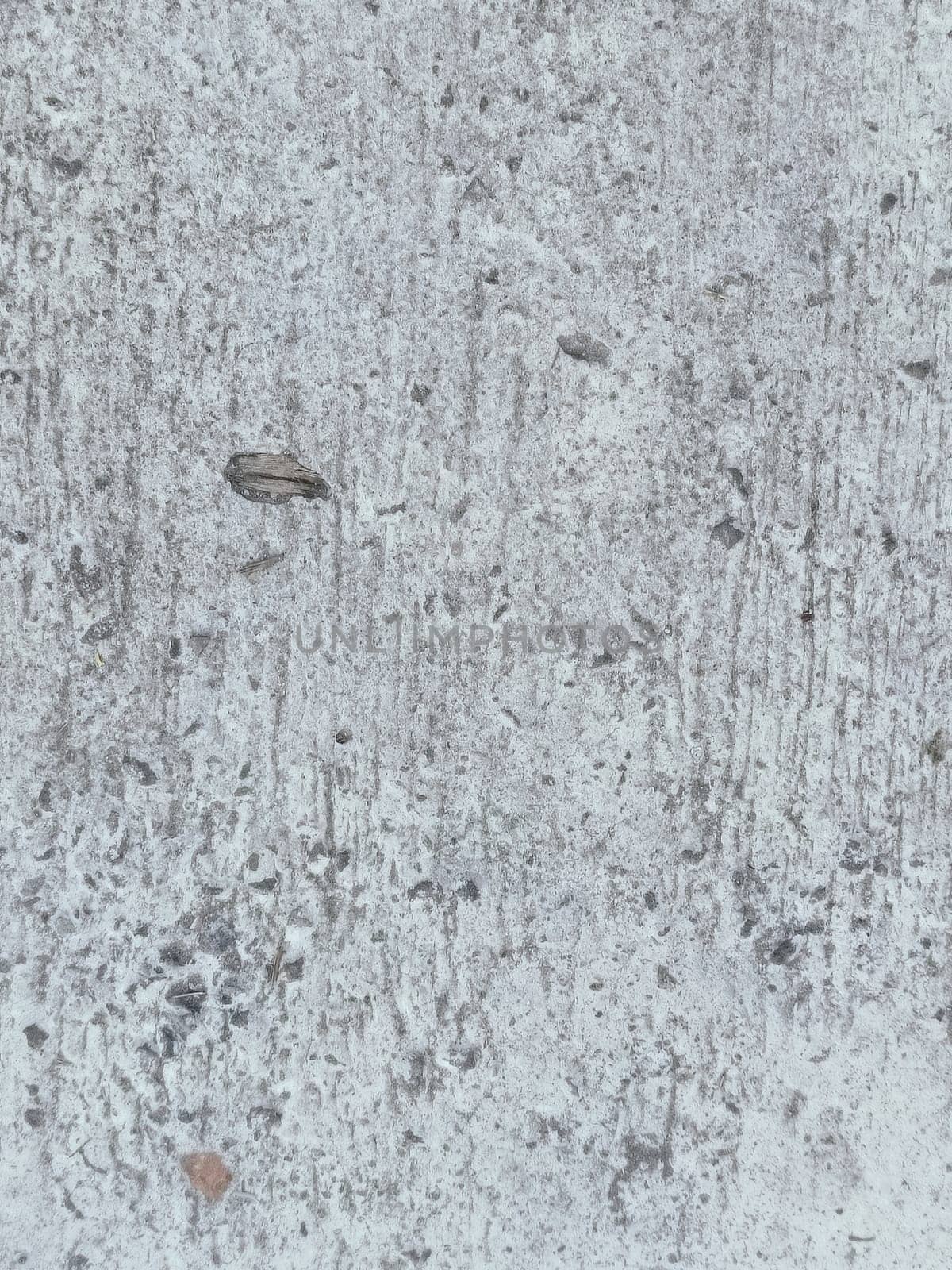 A grey and white wall with a few spots of color. The wall is made of concrete and has a rough texture