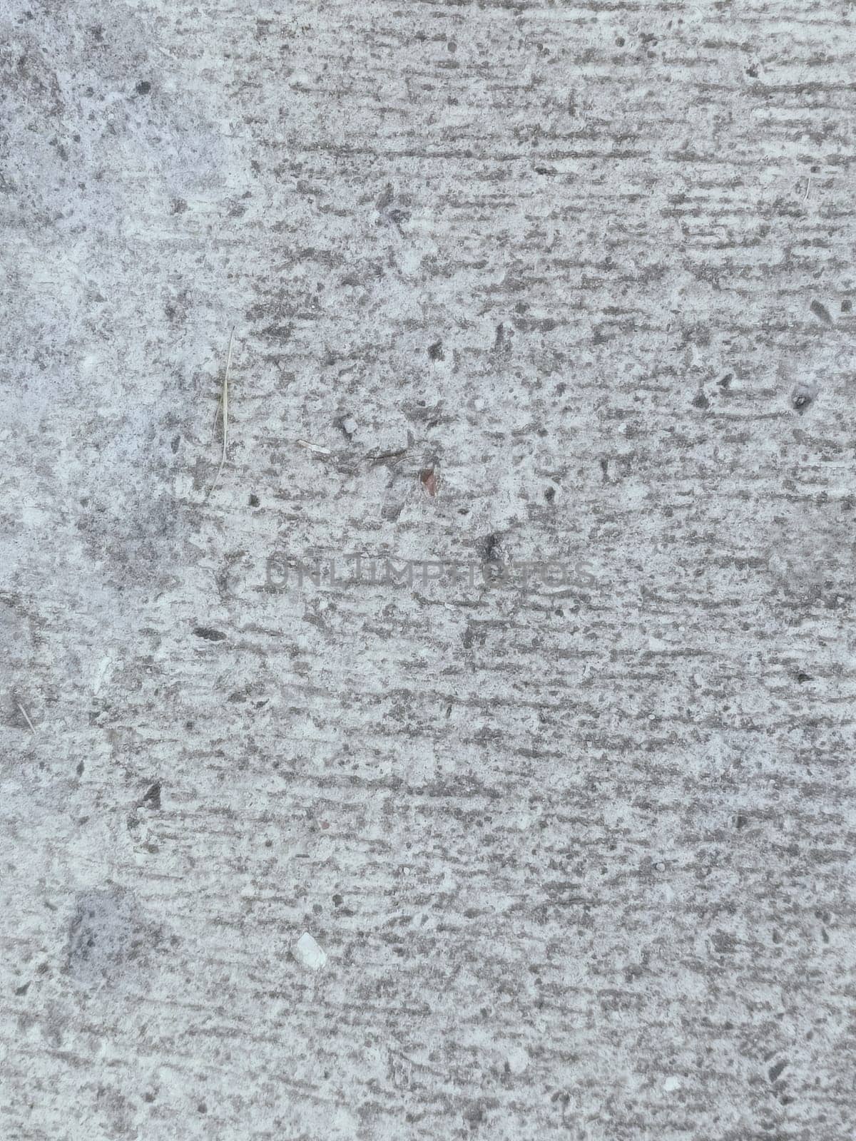 A grey and white wall with a few spots of color. The wall is made of concrete and has a rough texture