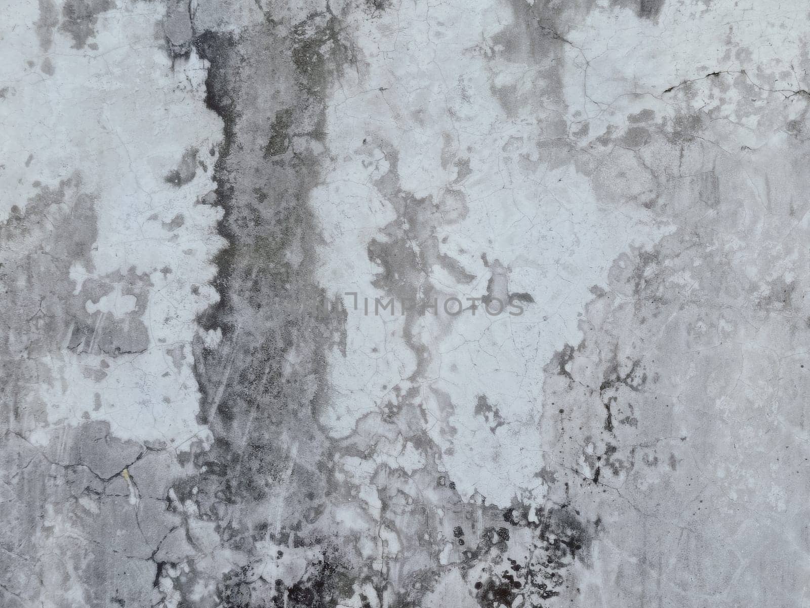 A grey and white wall with a few spots of color. The wall is made of concrete and has a rough texture