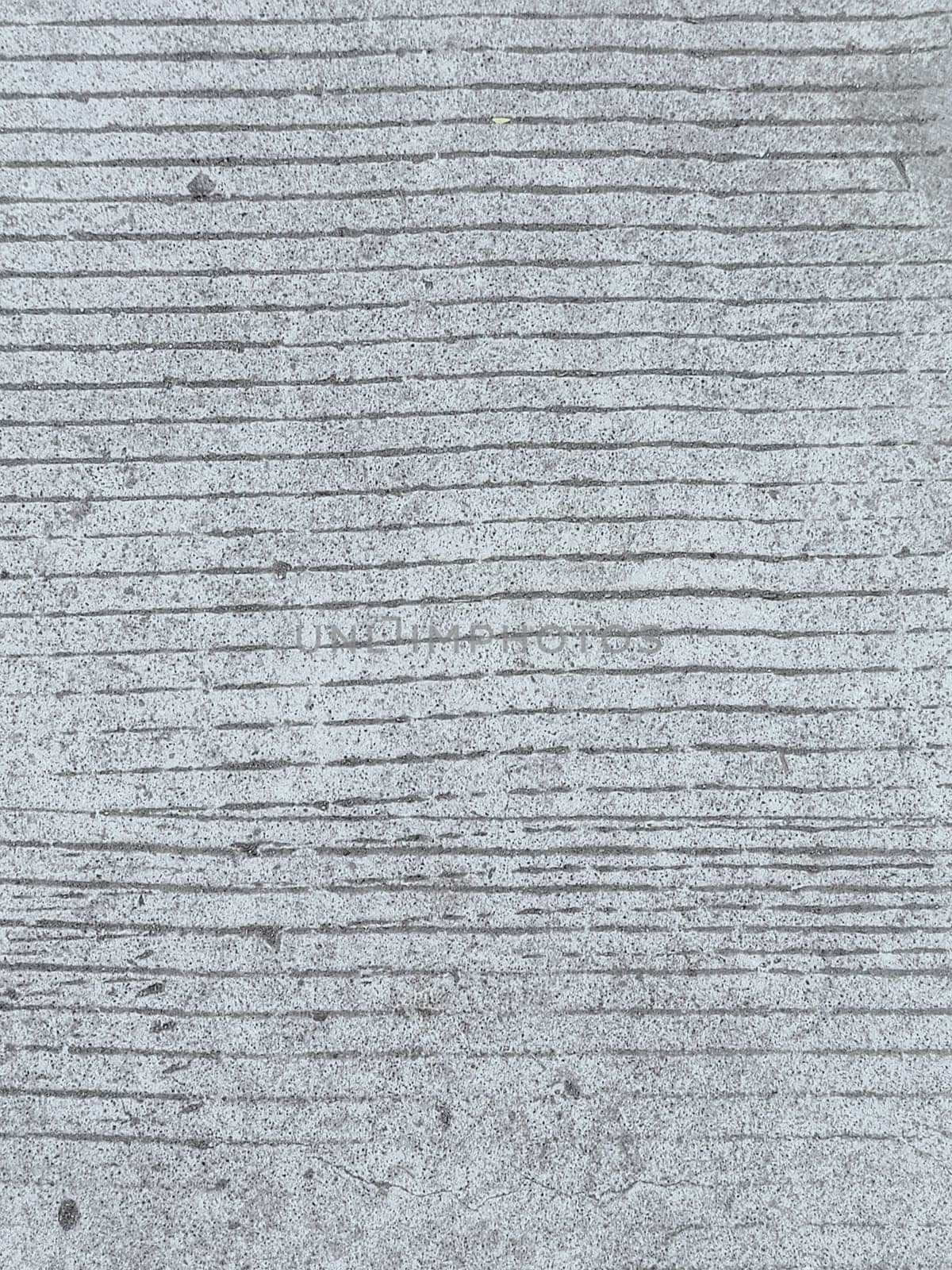 A grey and white wall with a few spots of color. The wall is made of concrete and has a rough texture