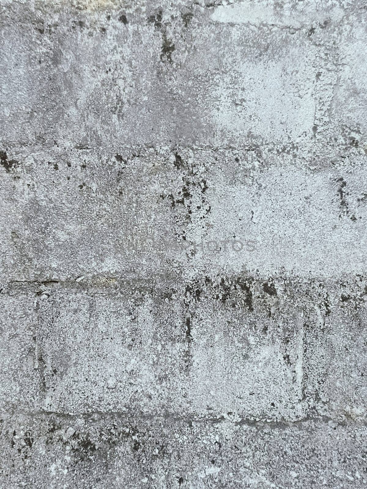 A grey and white wall with a few spots of color. The wall is made of concrete and has a rough texture