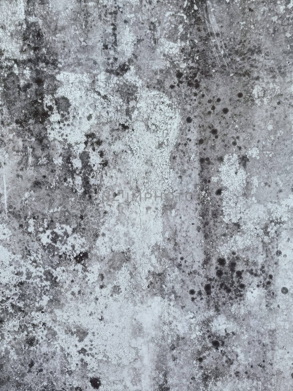 A grey and white wall with a few spots of color. The wall is made of concrete and has a rough texture