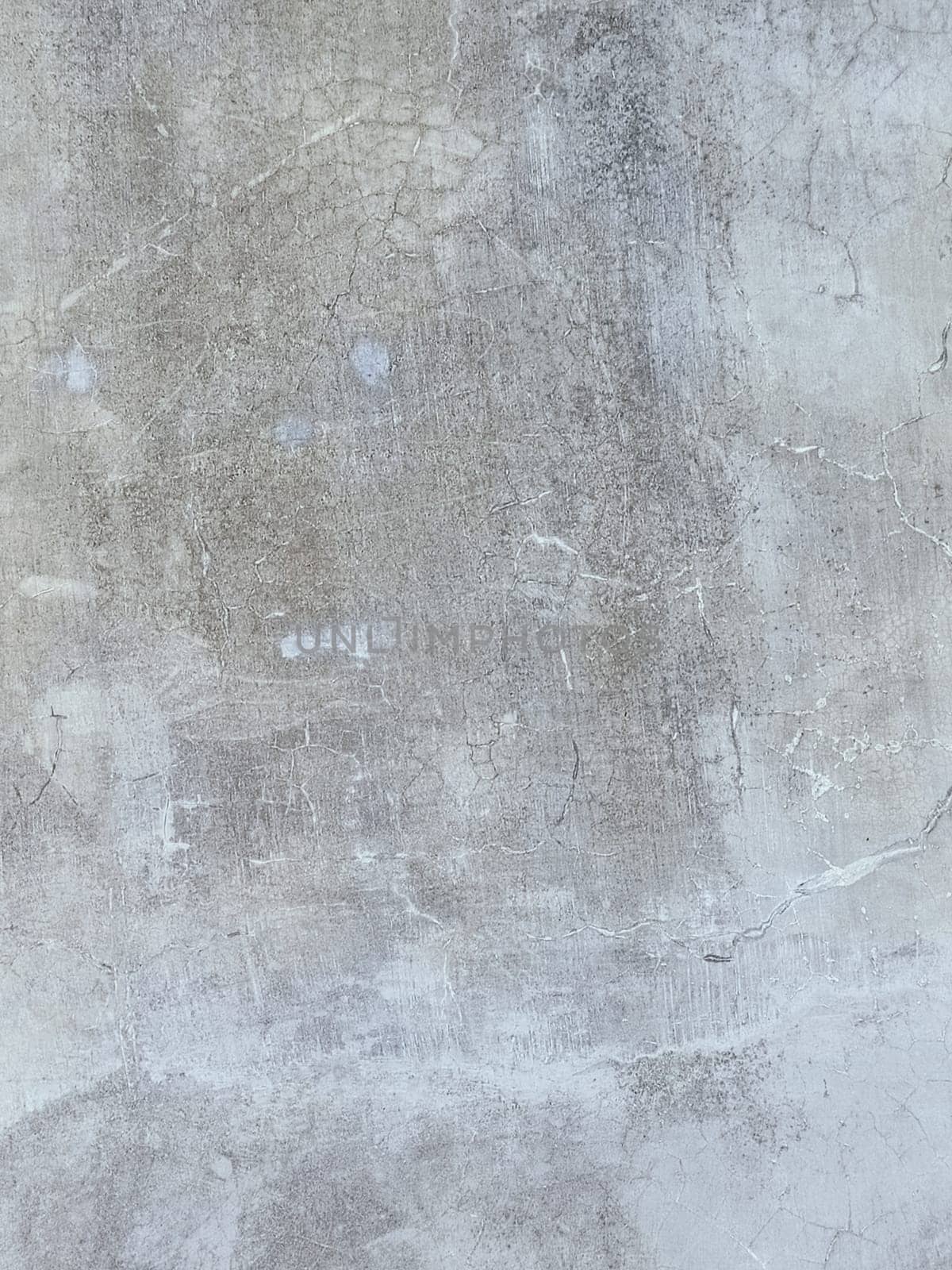A grey and white wall with a few spots of color. The wall is made of concrete and has a rough texture