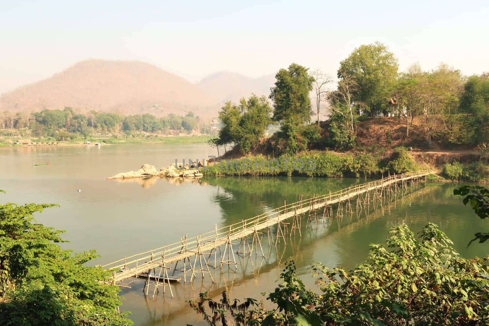 View from the old town on a traditional bamboo bridge over the Nam Khan River, the Mekong River in the background, Luang Prabang, Laos 2023