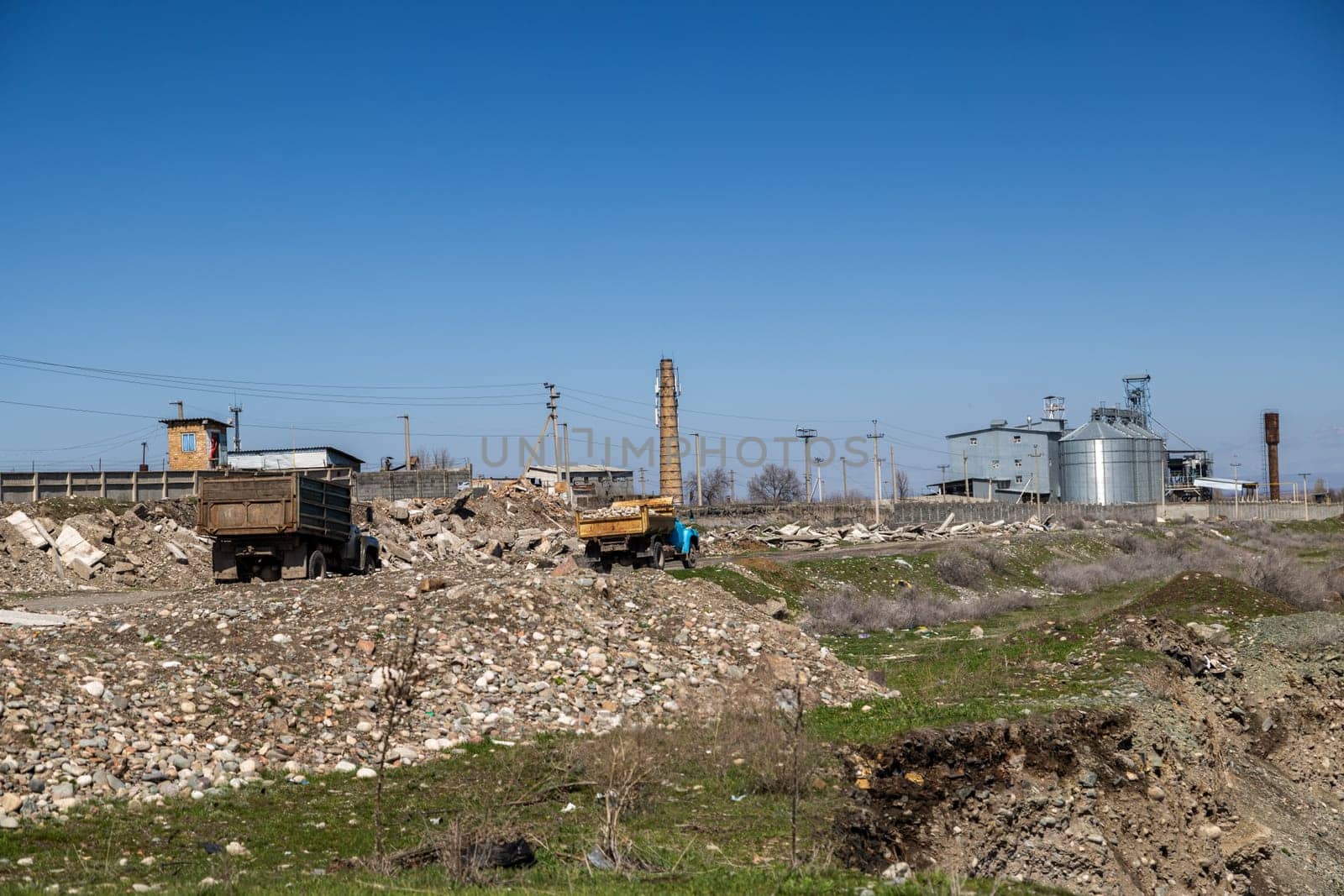 two old soviet trucks driving stones along concrete rubble trough Industrial area at sunny day