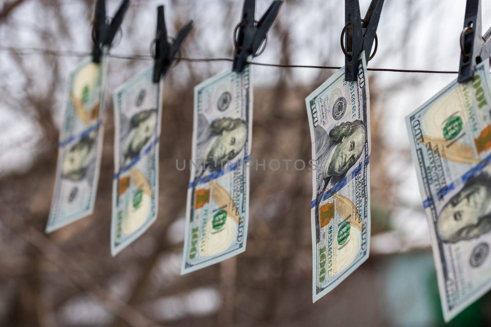 hundred-dollar bills hanging on a clothesline, secured with clothespins, symbolizing money laundering or financial dealings