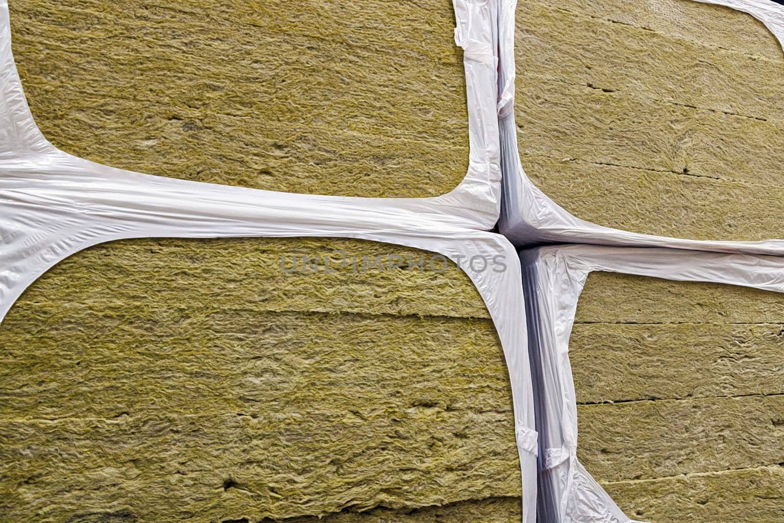 Stack of glass wool insulation stacks in white shrink wrap. Stack of fiberglass insulation material. Mineral wool insulator for heat and cold protection.