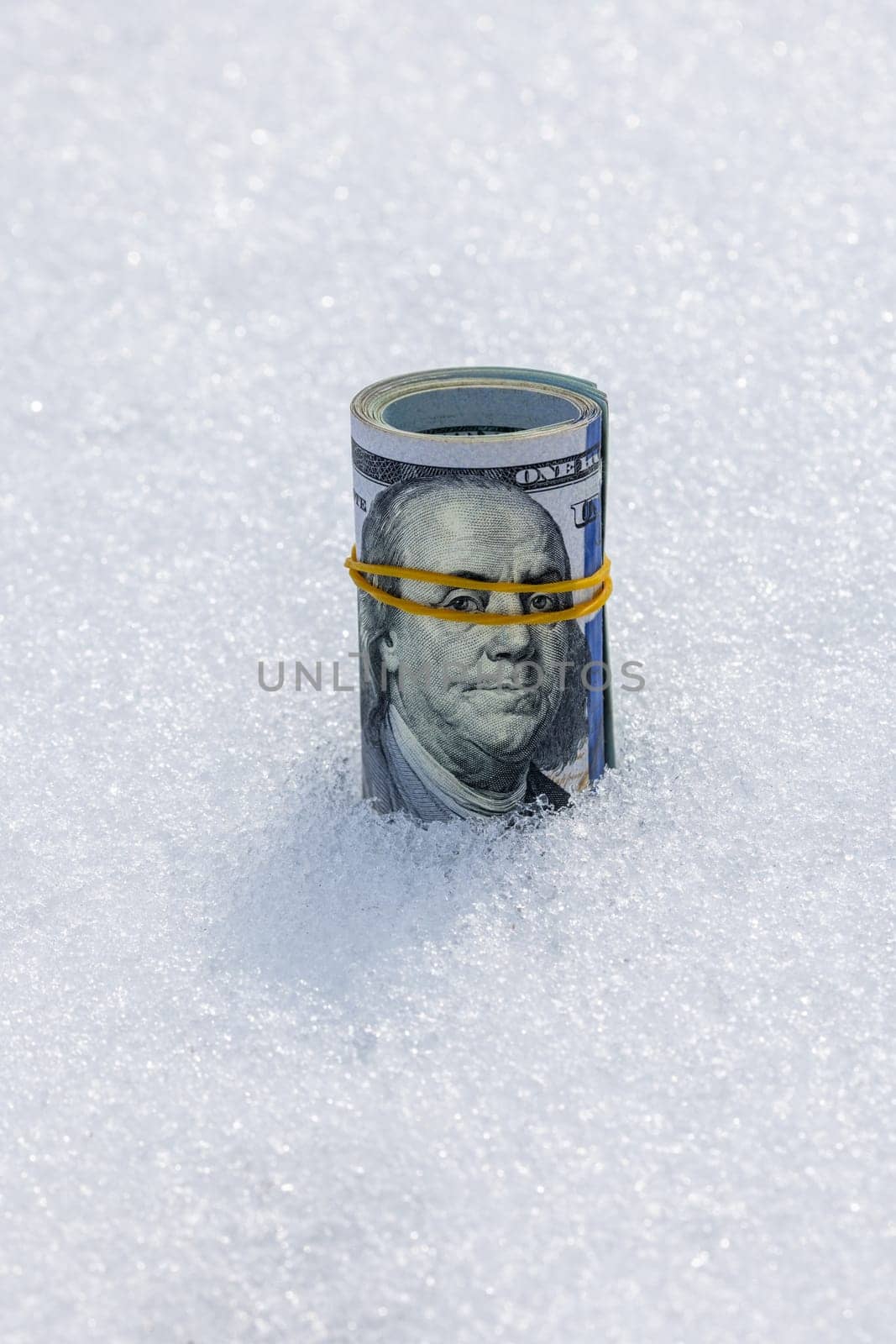 A roll of real cash standing on a snow surface at sunny winter day.