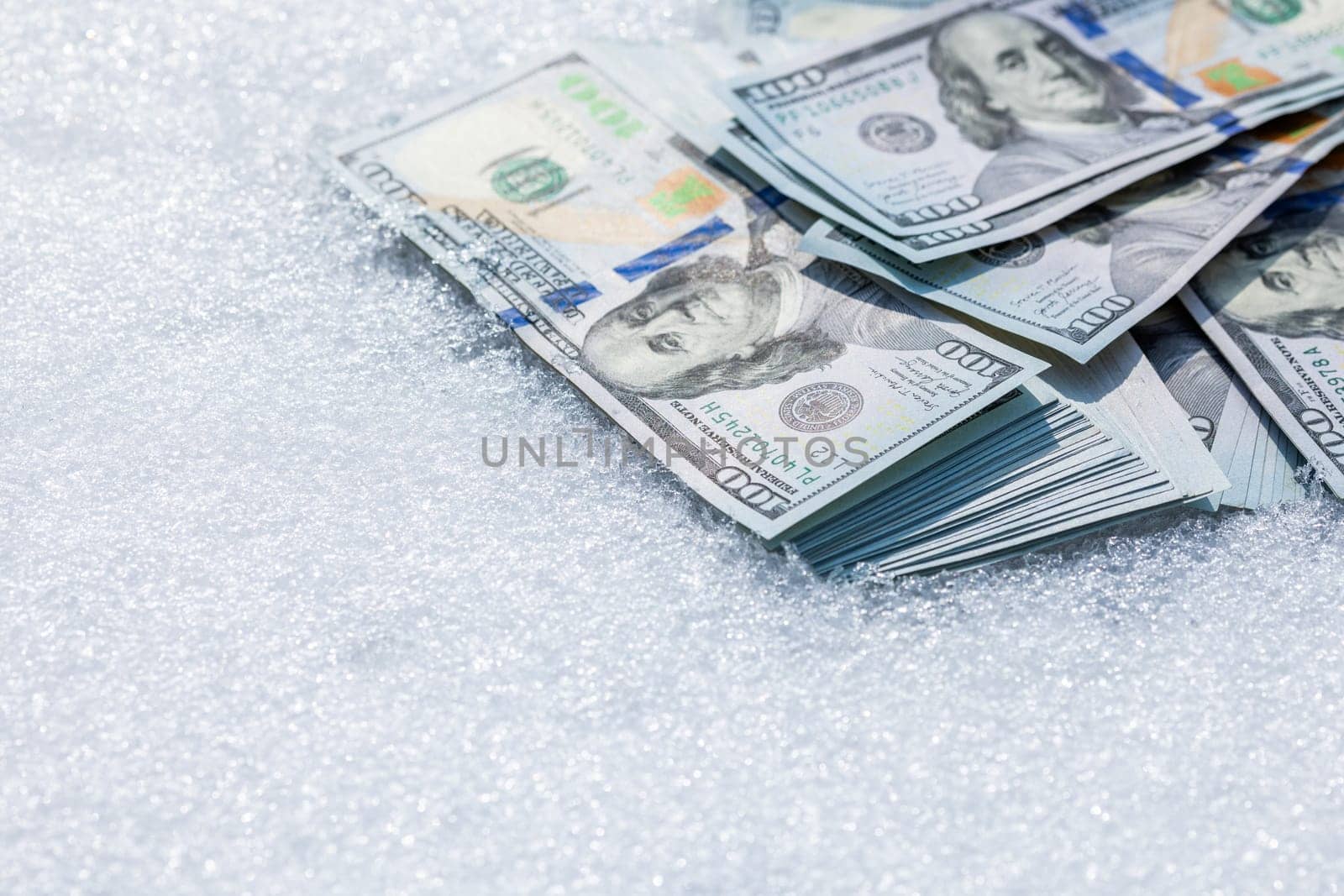 A bundle of cash lying on a snow surface at sunny winter day