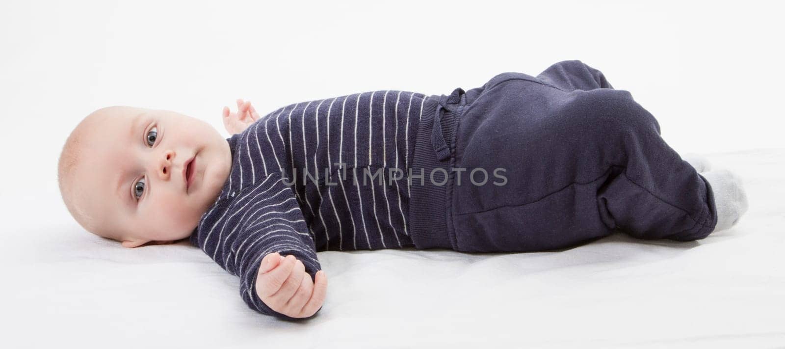 smiling toddler in blue clothing laying down. vertical image