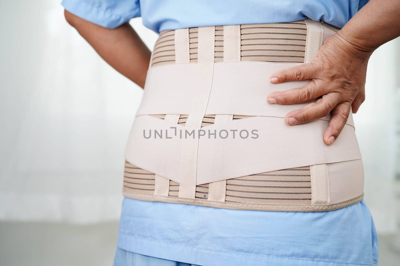 Asian senior wearing elastic support belt can help reduce back pain.