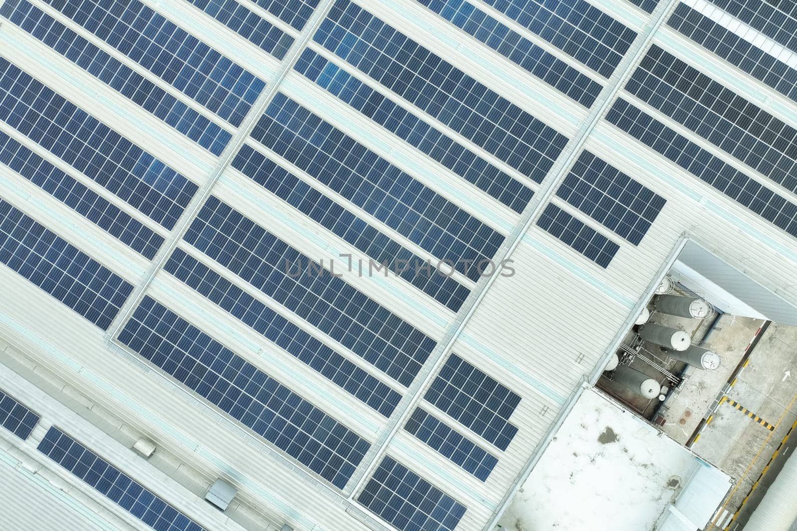 Solar energy for factory and warehouse building. Solar panels on roof of industrial plant. Commercial solar power. Rooftop solar power. Rooftop renewable energy system. Sustainable green energy.