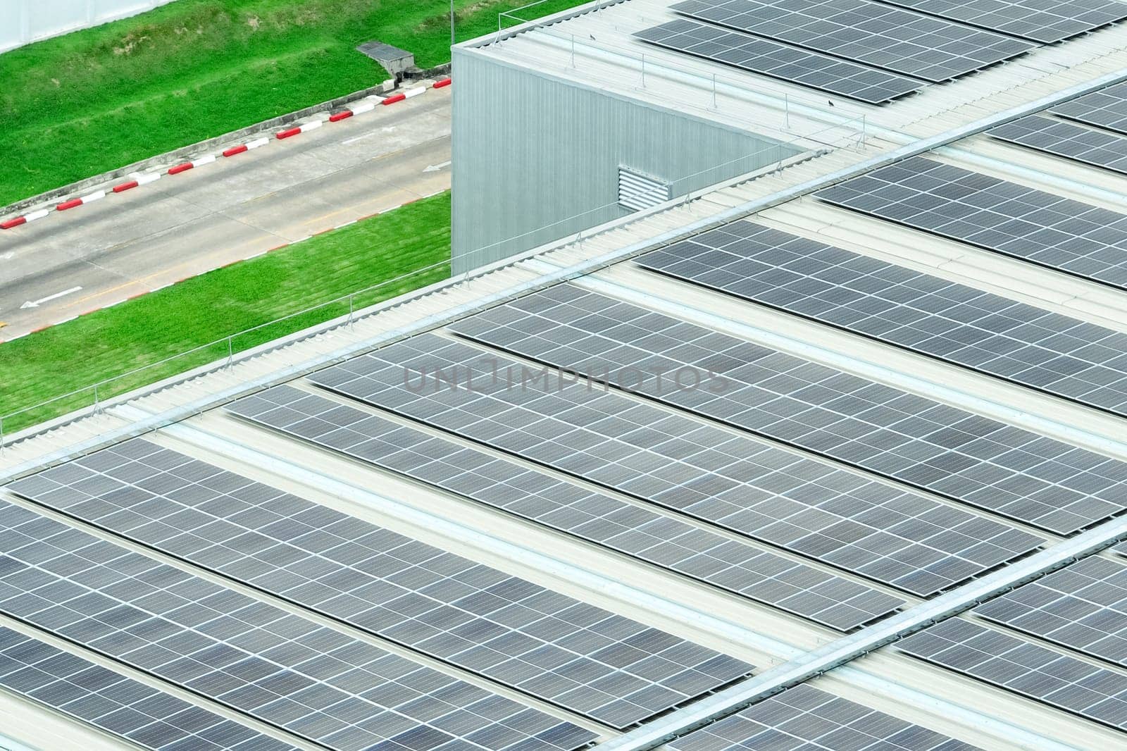 Solar energy for factory and warehouse building. Solar panels on roof of industrial plant. Commercial solar power. Rooftop solar power. Rooftop renewable energy system. Sustainable green energy.