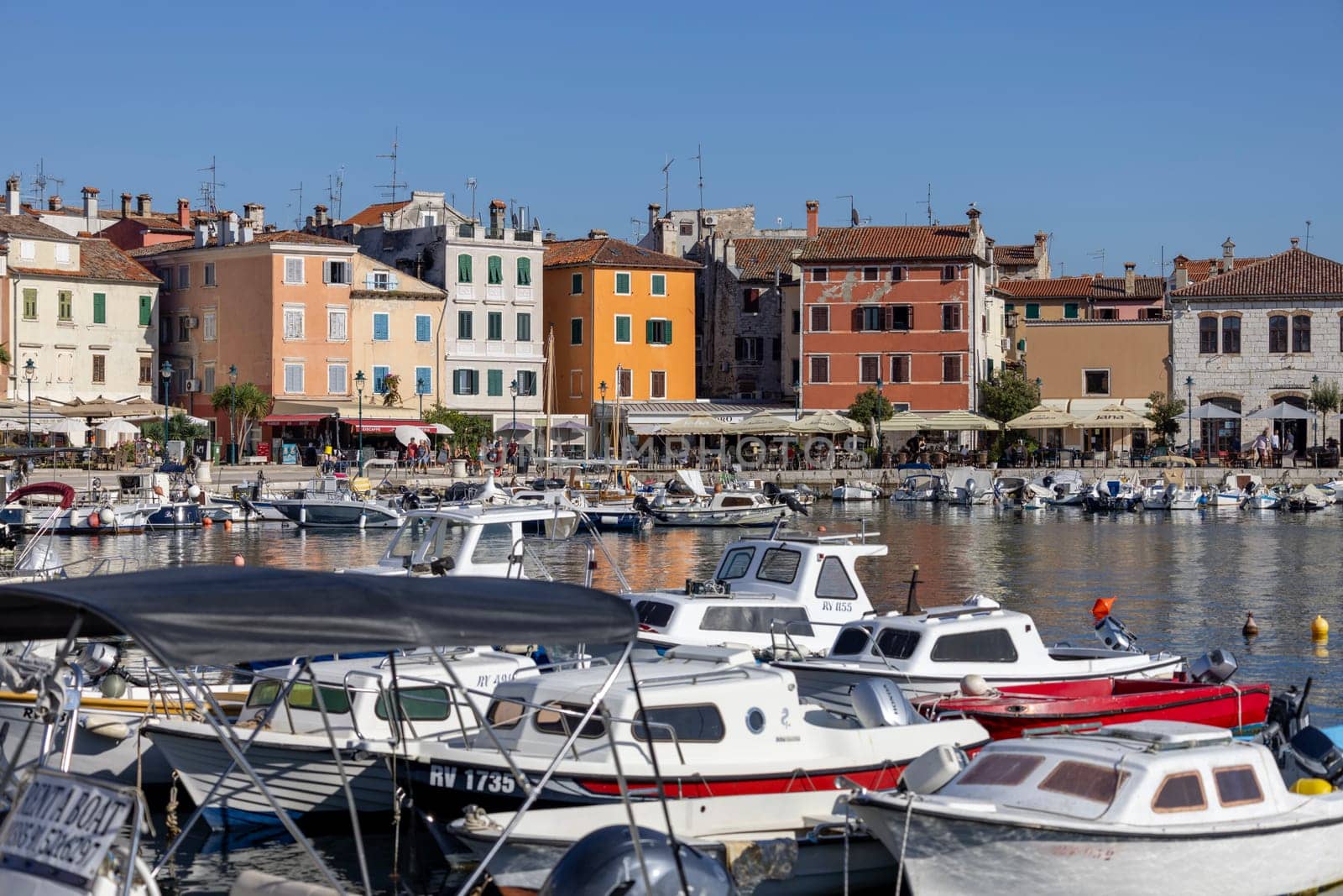 Rovinj, Croatia, Istria - September 29, 2023: Colorful tenement houses on the boulevard by the South port Rovinj over Adriatic Sea, moored boats
