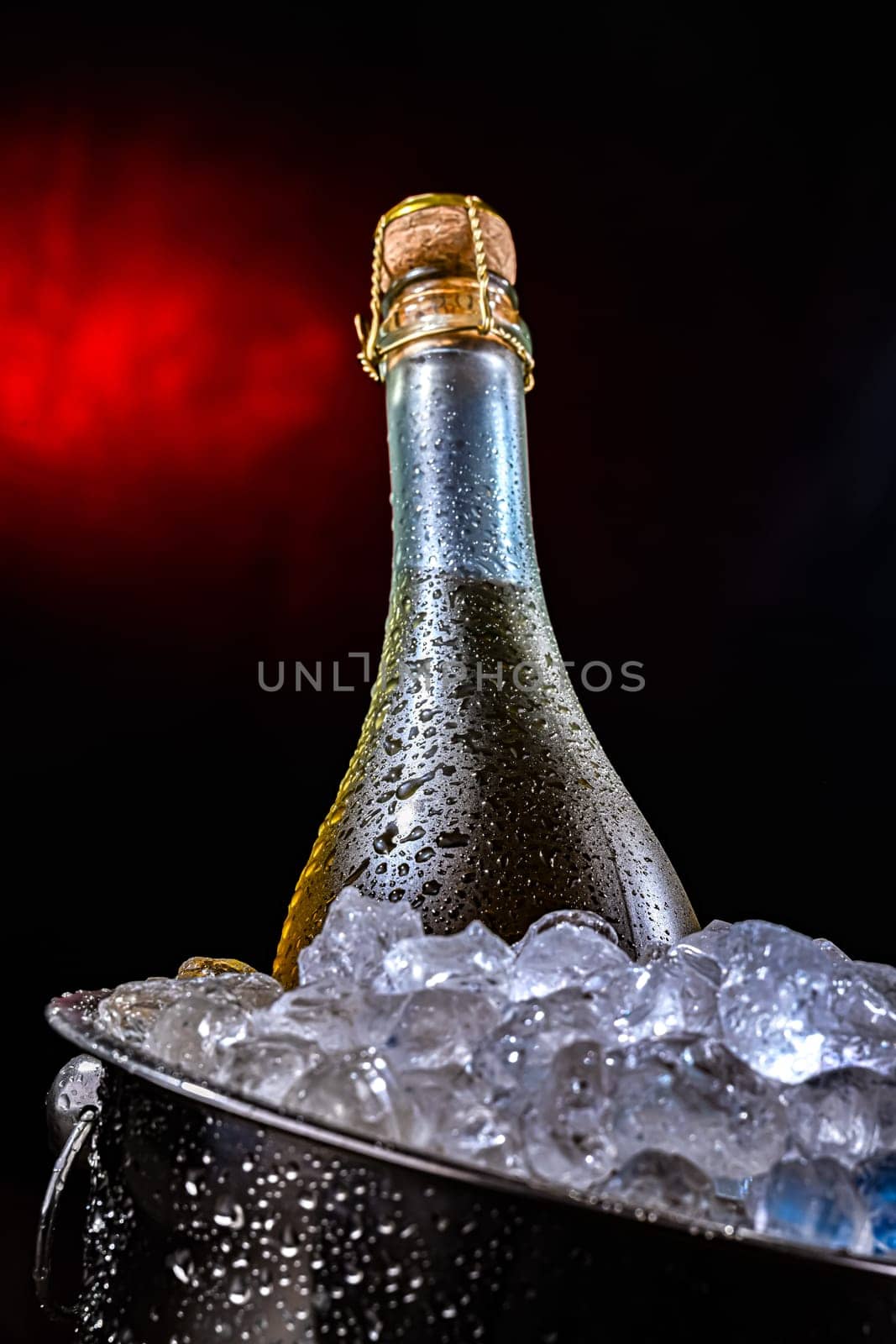 Bottle of sparkiling wine in bucket with crushed ice.