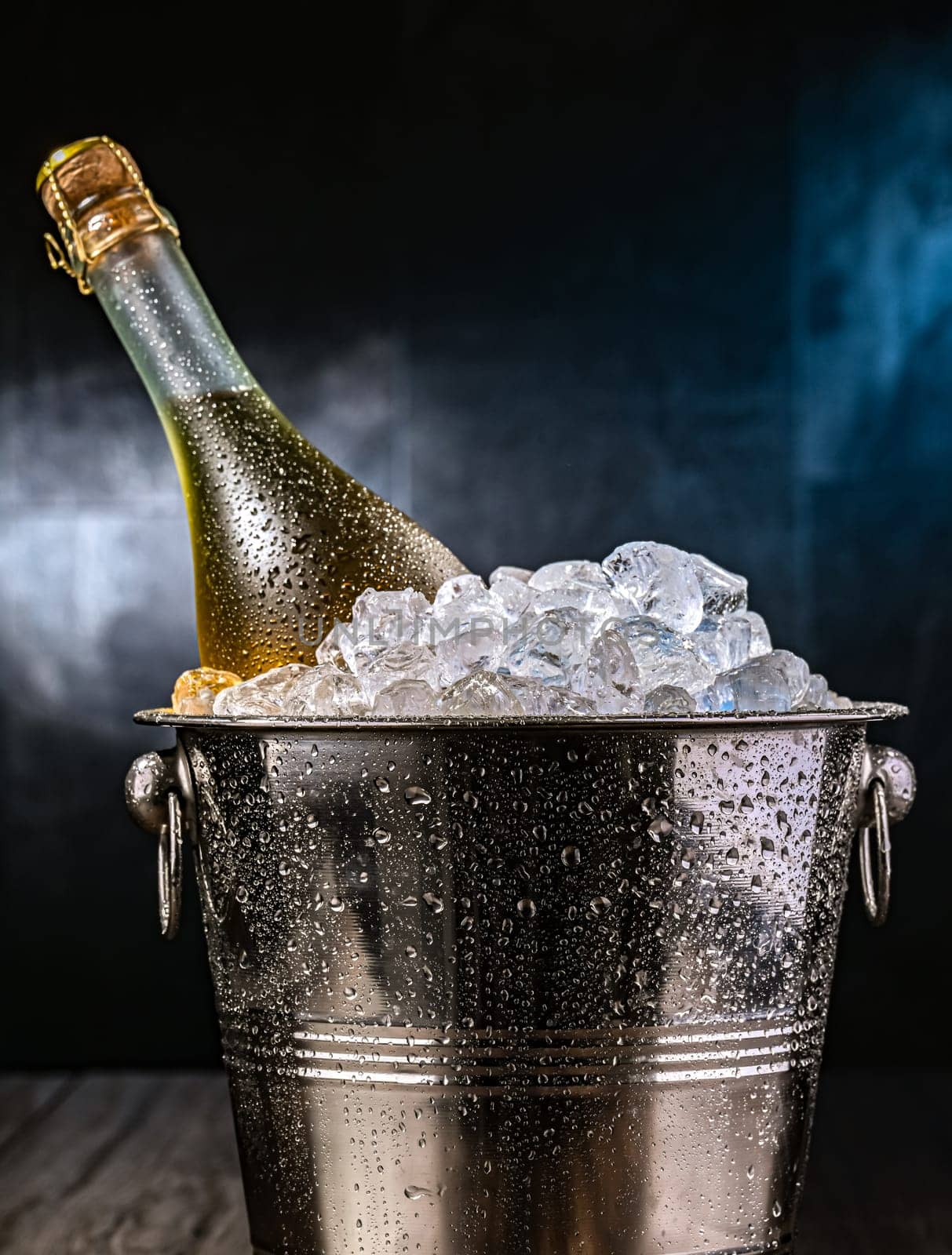 Bottle of sparkiling wine in bucket with crushed ice.