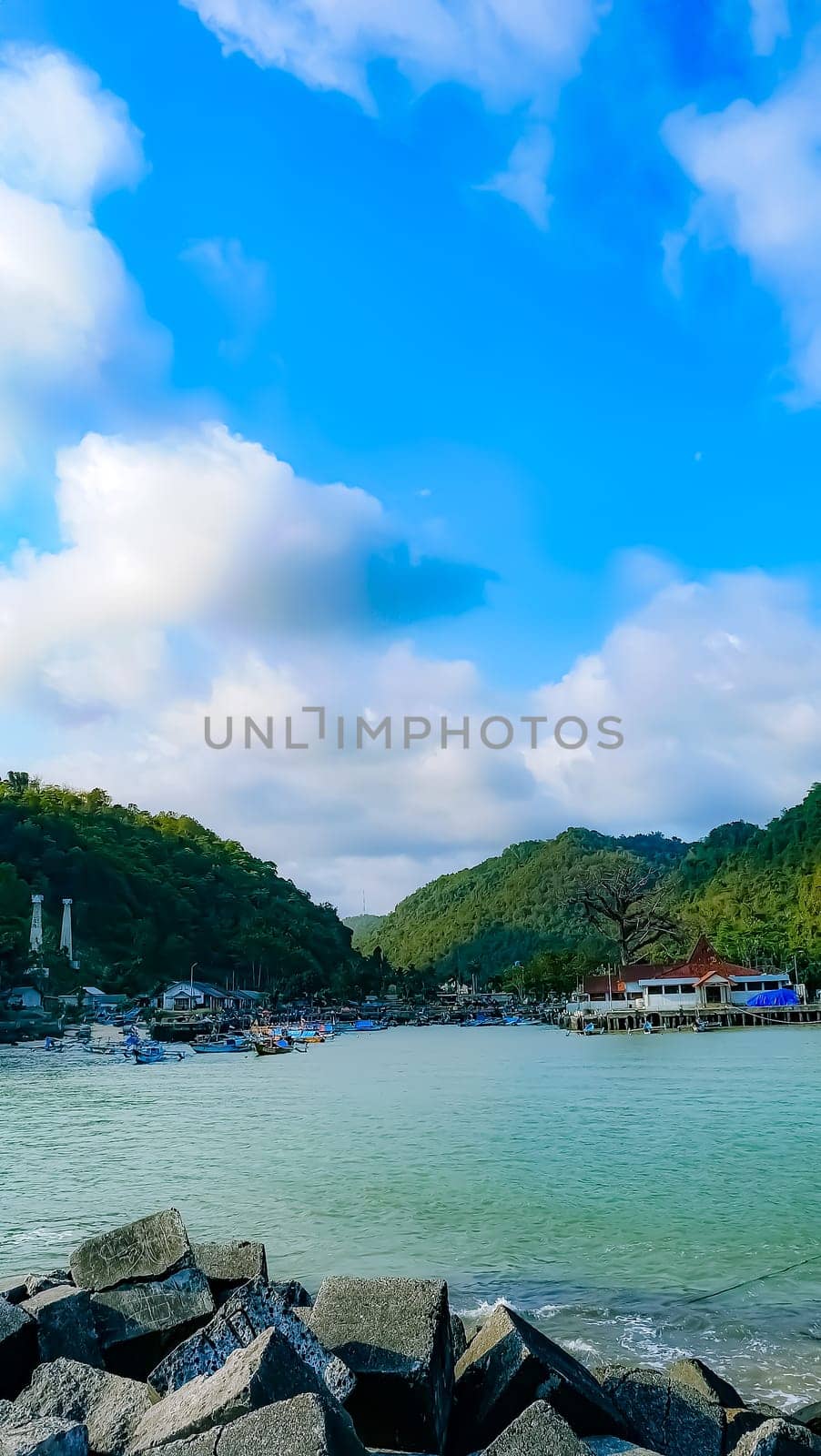 A large group of boats are floating on a lake. The sky is blue with some clouds