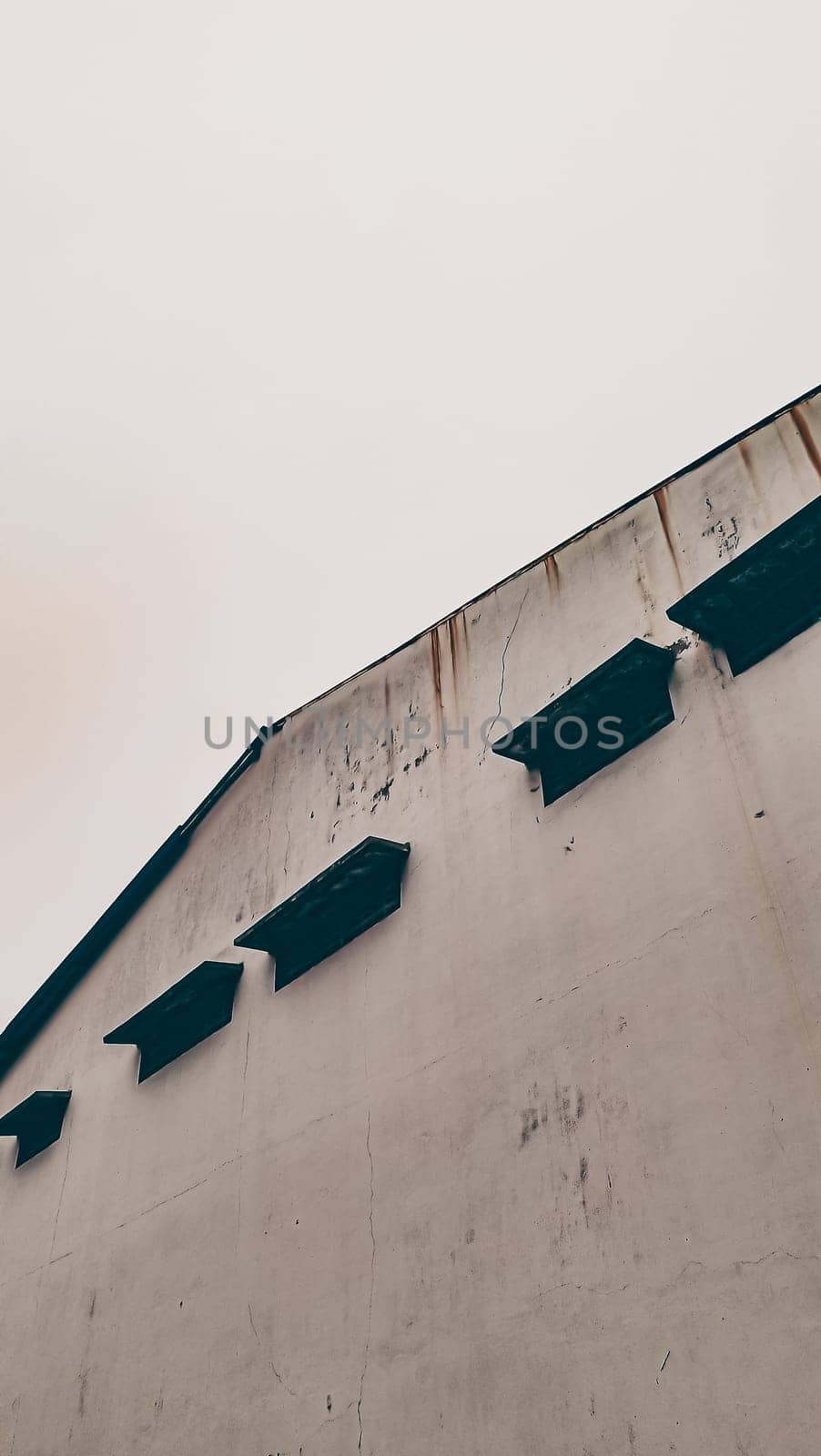 A minimalist view of a weathered industrial warehouse exterior with simple, clean lines and architectural details that evoke a vintage, rustic charm under a soft, overcast sky.