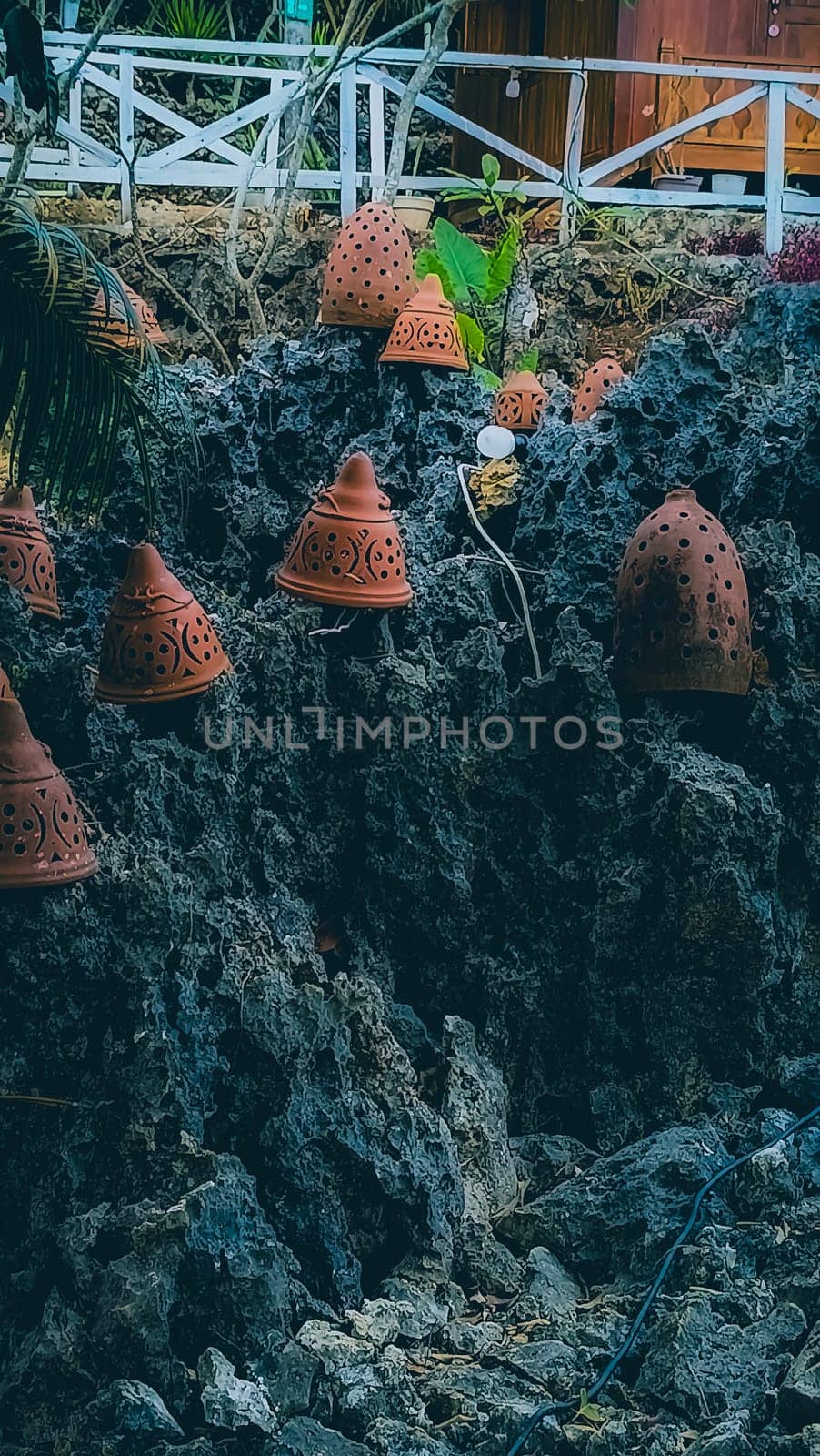 Decorative terracotta pots placed on rugged, rocky terrain juxtaposed with lush green foliage, creating a rustic and artistic outdoor scene. Ideal for themes of nature, craftsmanship, and aesthetics.