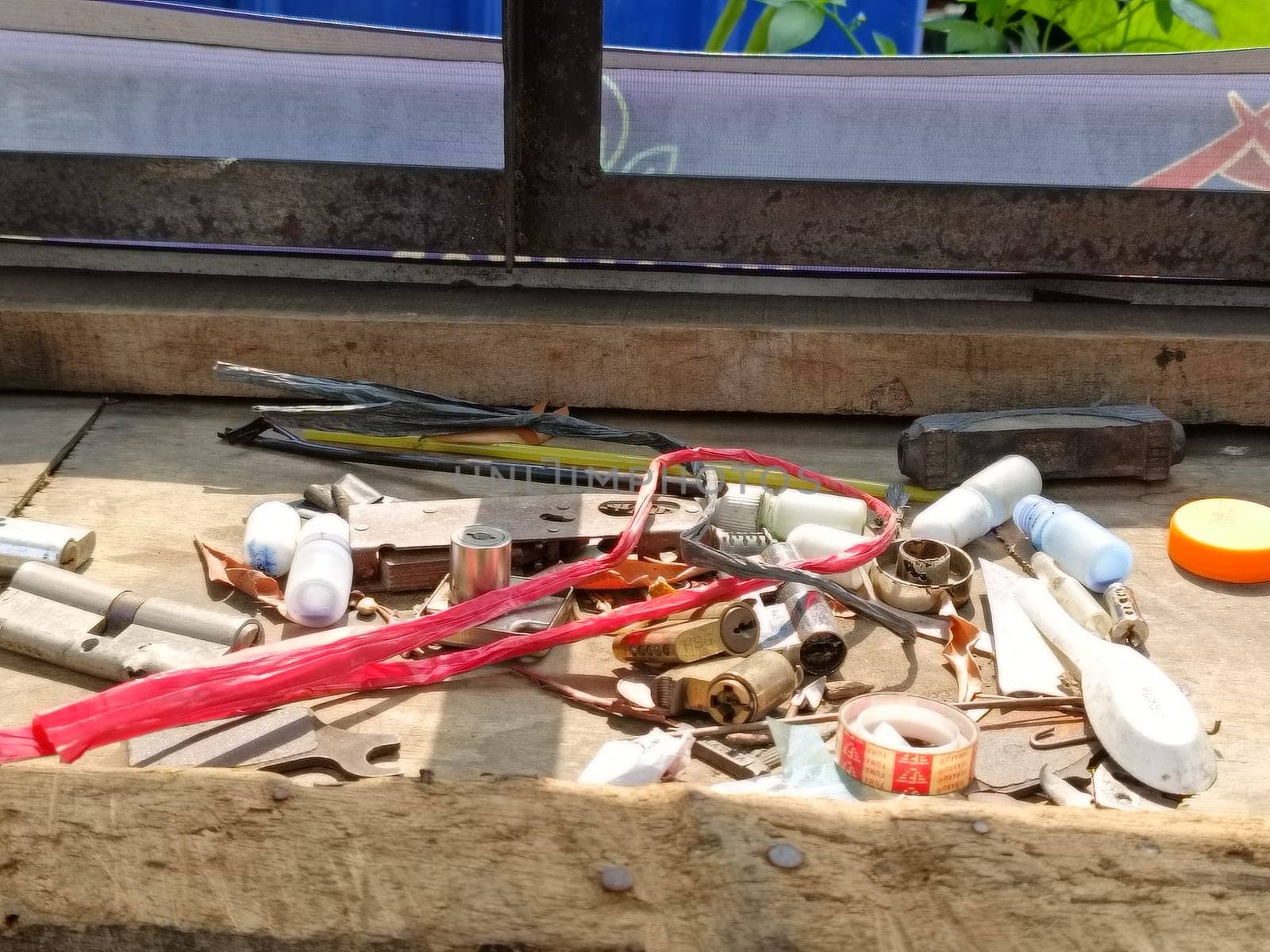 A collection of various tools and hardware scattered on a wooden bench. Items include wires, bulbs, and small parts, suggesting a workshop or DIY project setting.