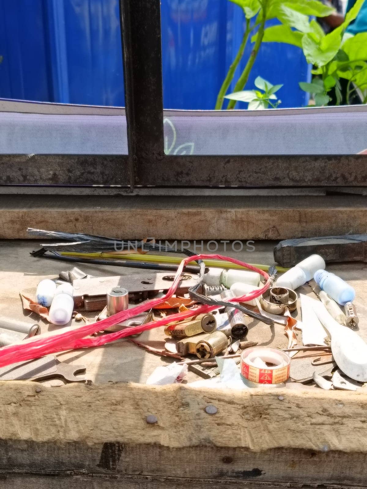 A collection of various tools and hardware scattered on a wooden bench. Items include wires, bulbs, and small parts, suggesting a workshop or DIY project setting.
