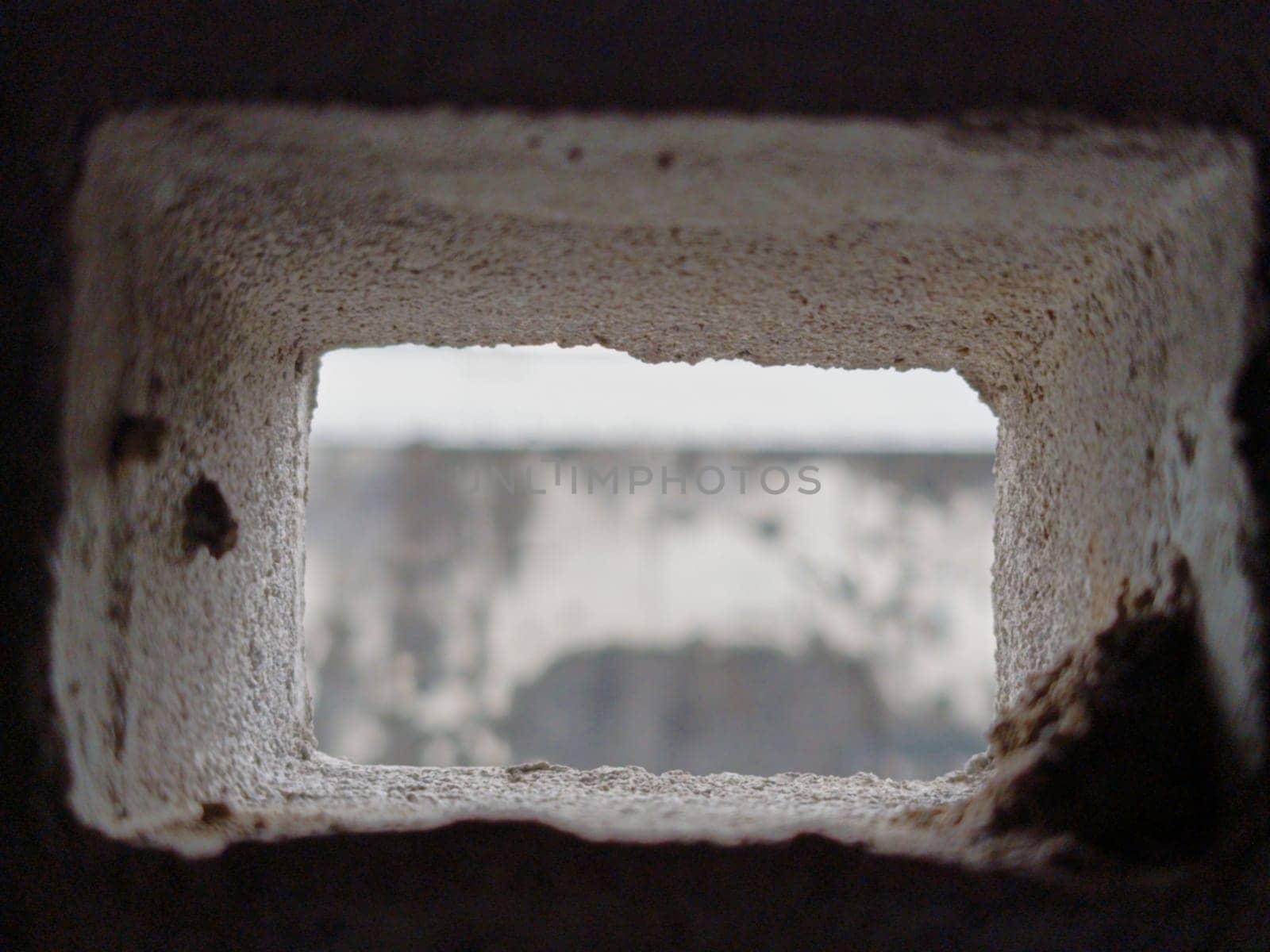 Abstract view through a grid of concrete blocks, showcasing the interplay of light and shadow. The geometric pattern offers an industrial and textured aesthetic, creating a sense of confinement and openness.