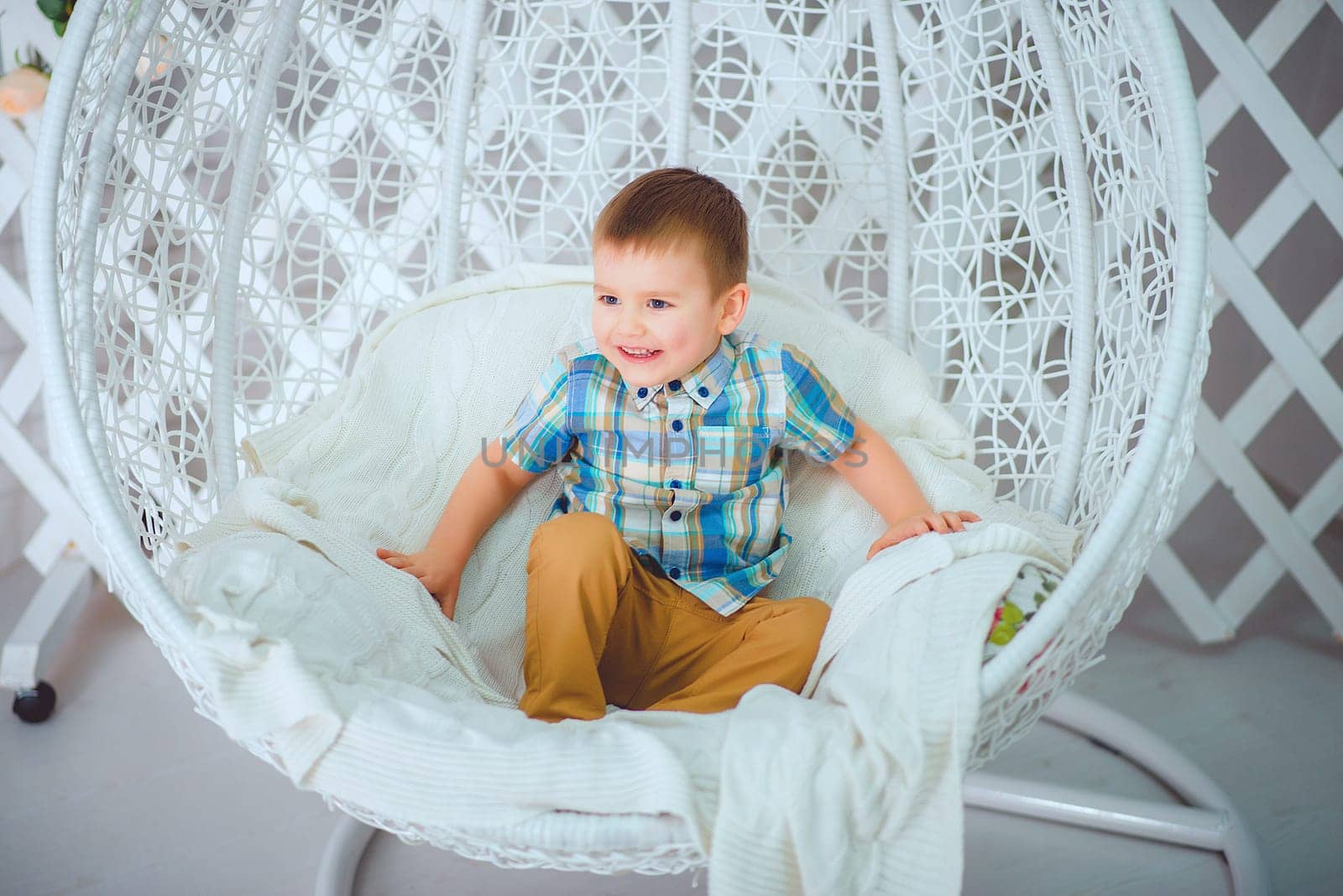 A cheerful and happy child joyfully sitting in a cozy hanging chair, showcasing playful vibes and ultimate comfort