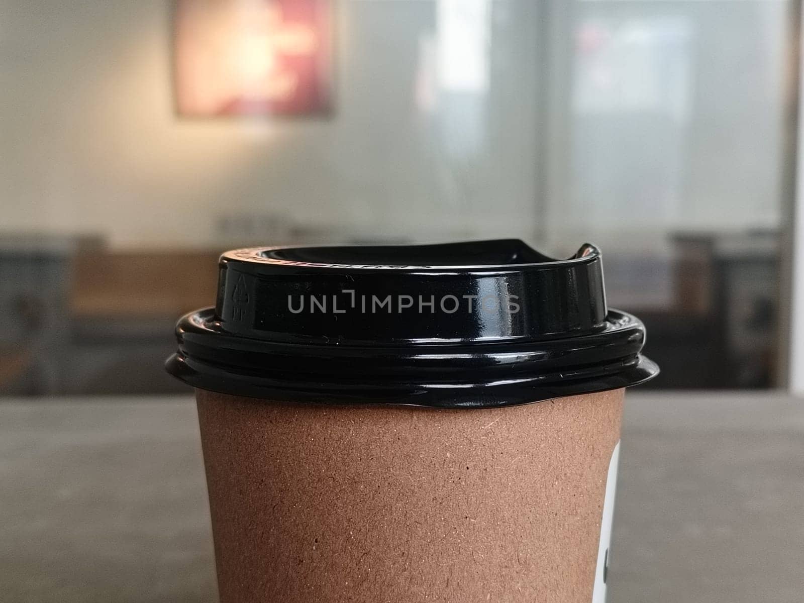 Simple brown paper coffee cup with black plastic lid, ideal for takeaway beverages. Represents convenience, modern lifestyle, and daily routines. Perfect for cafes and coffee shops imagery.