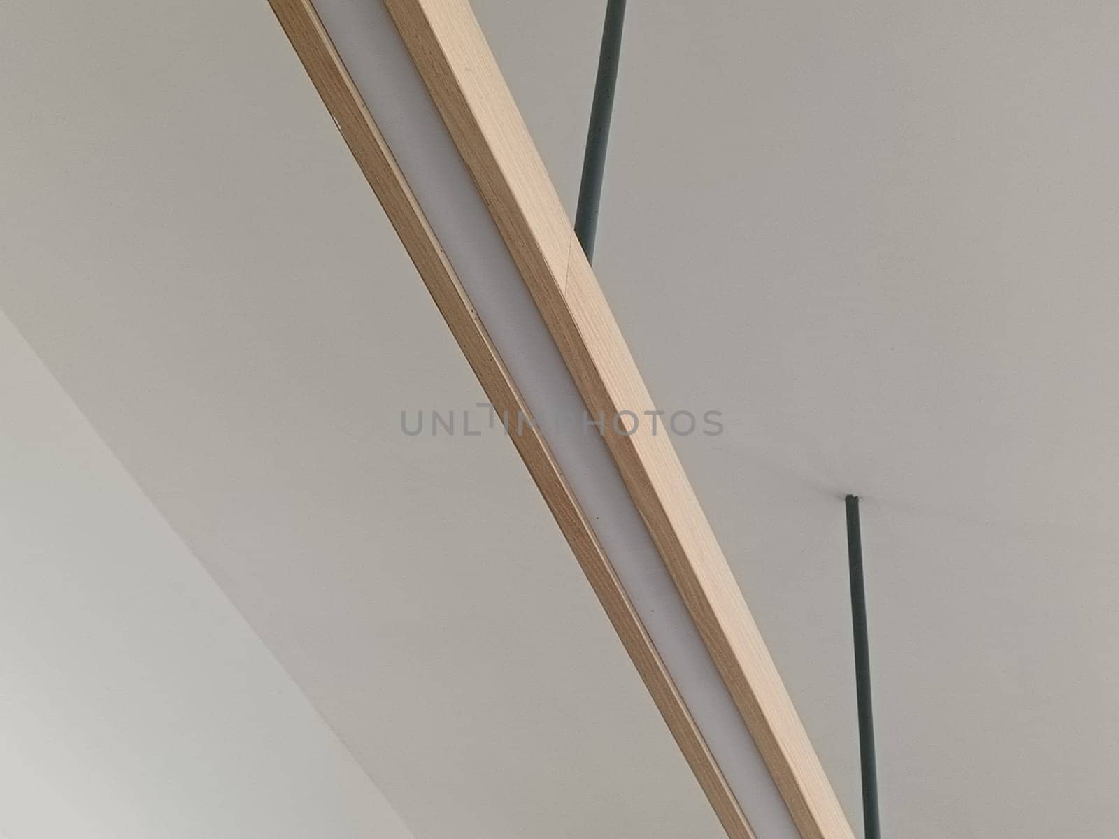 A close-up image of a modern minimalist ceiling light fixture with sleek lines and wooden accents, perfect for contemporary interior decor.