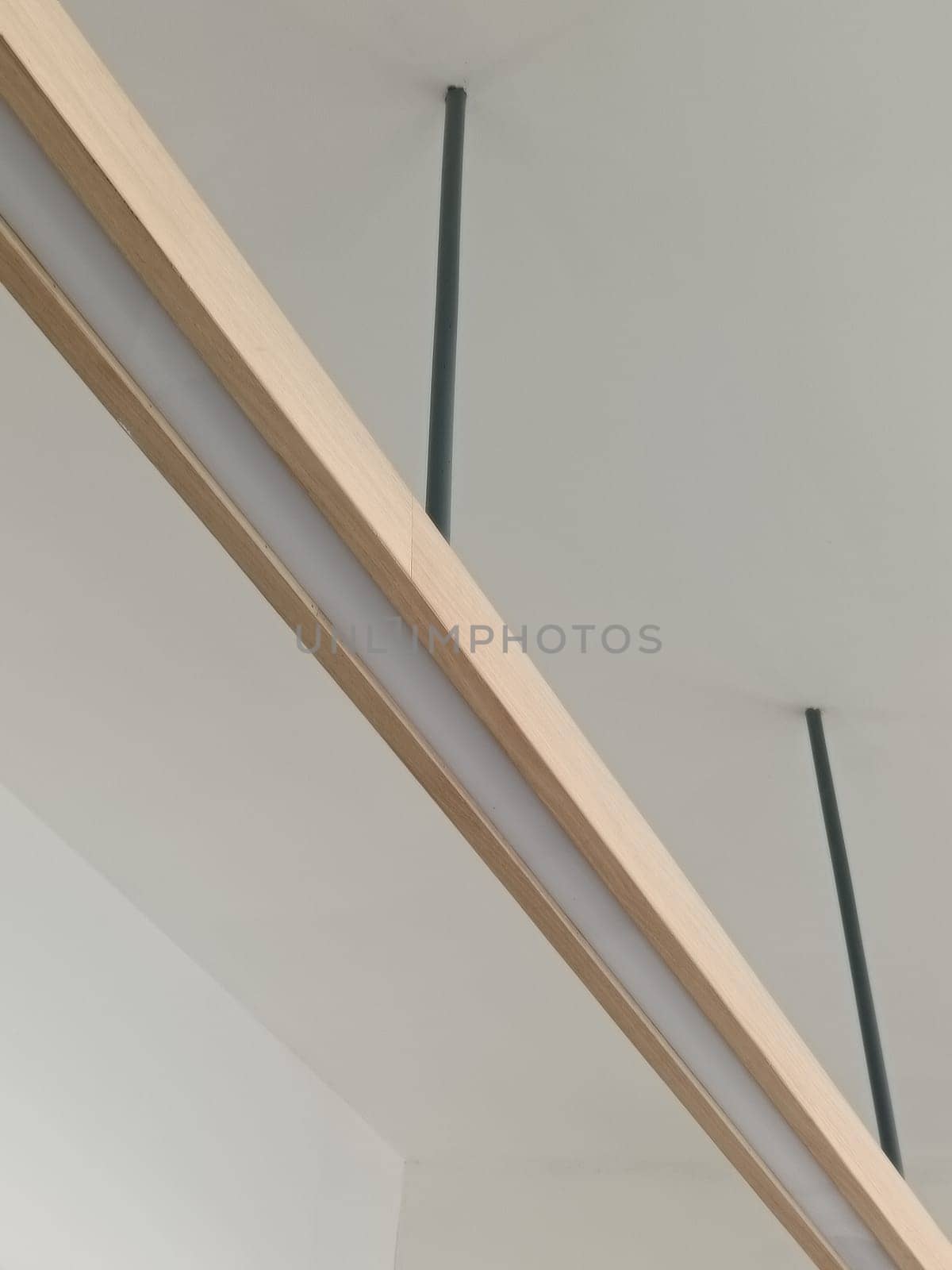 A close-up image of a modern minimalist ceiling light fixture with sleek lines and wooden accents, perfect for contemporary interior decor.