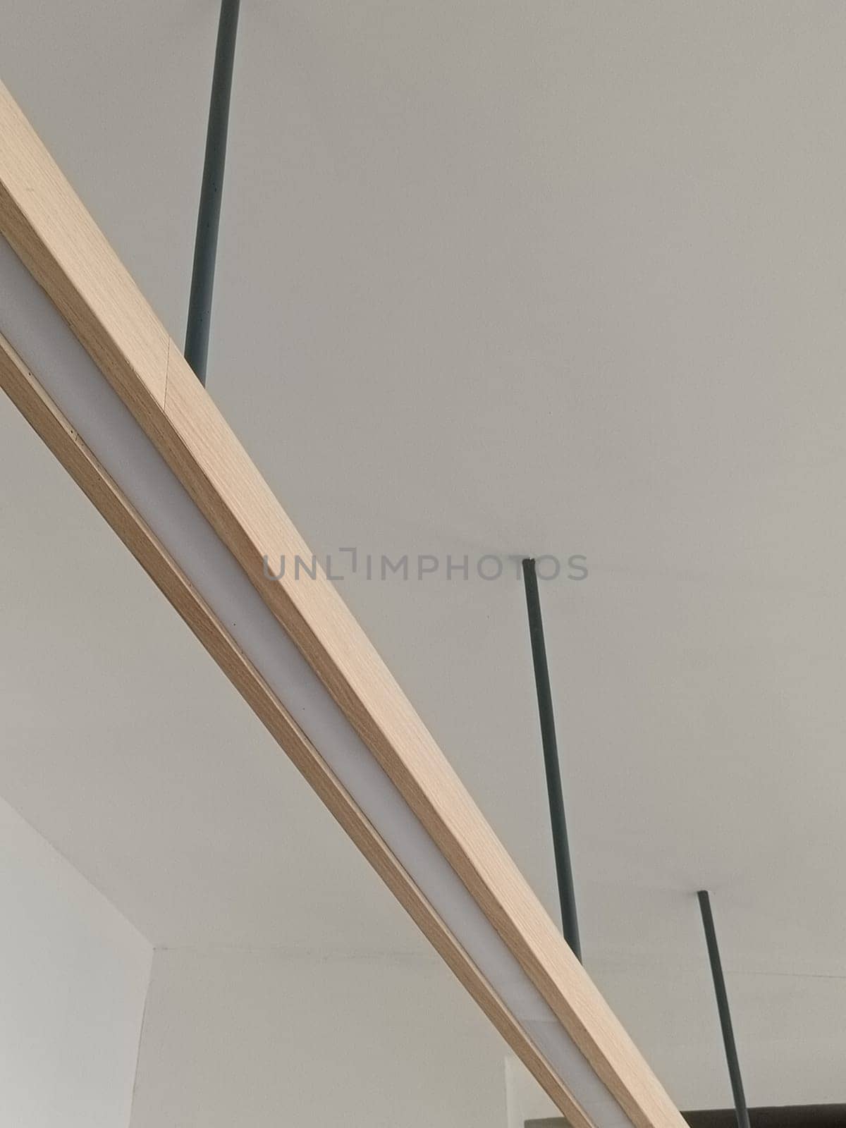 A close-up image of a modern minimalist ceiling light fixture with sleek lines and wooden accents, perfect for contemporary interior decor.