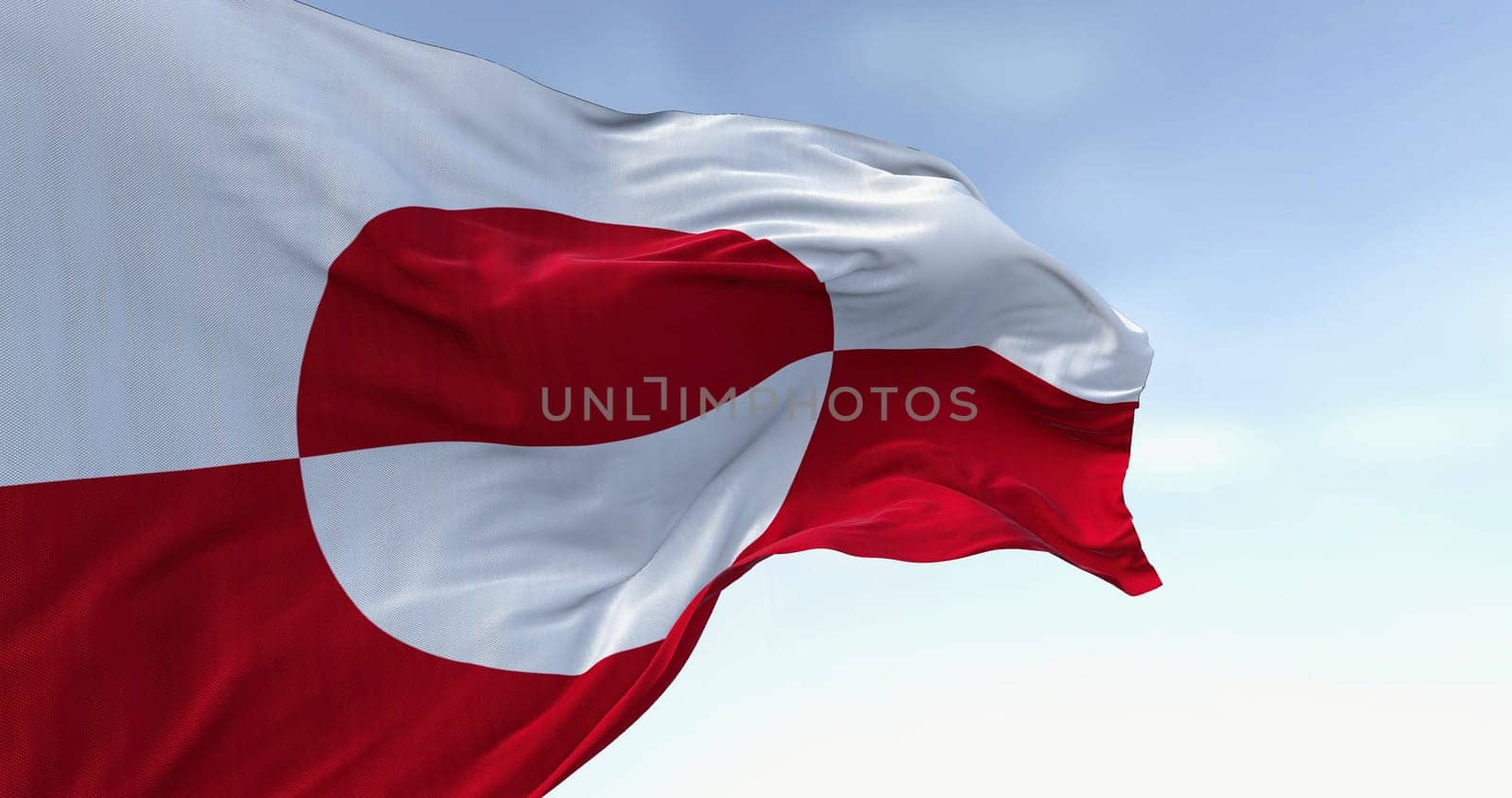The flag of Greenland waving in the wind on a clear day. Greenland is the world's largest island, and one of the three constituent countries that form the Kingdom of Denmark