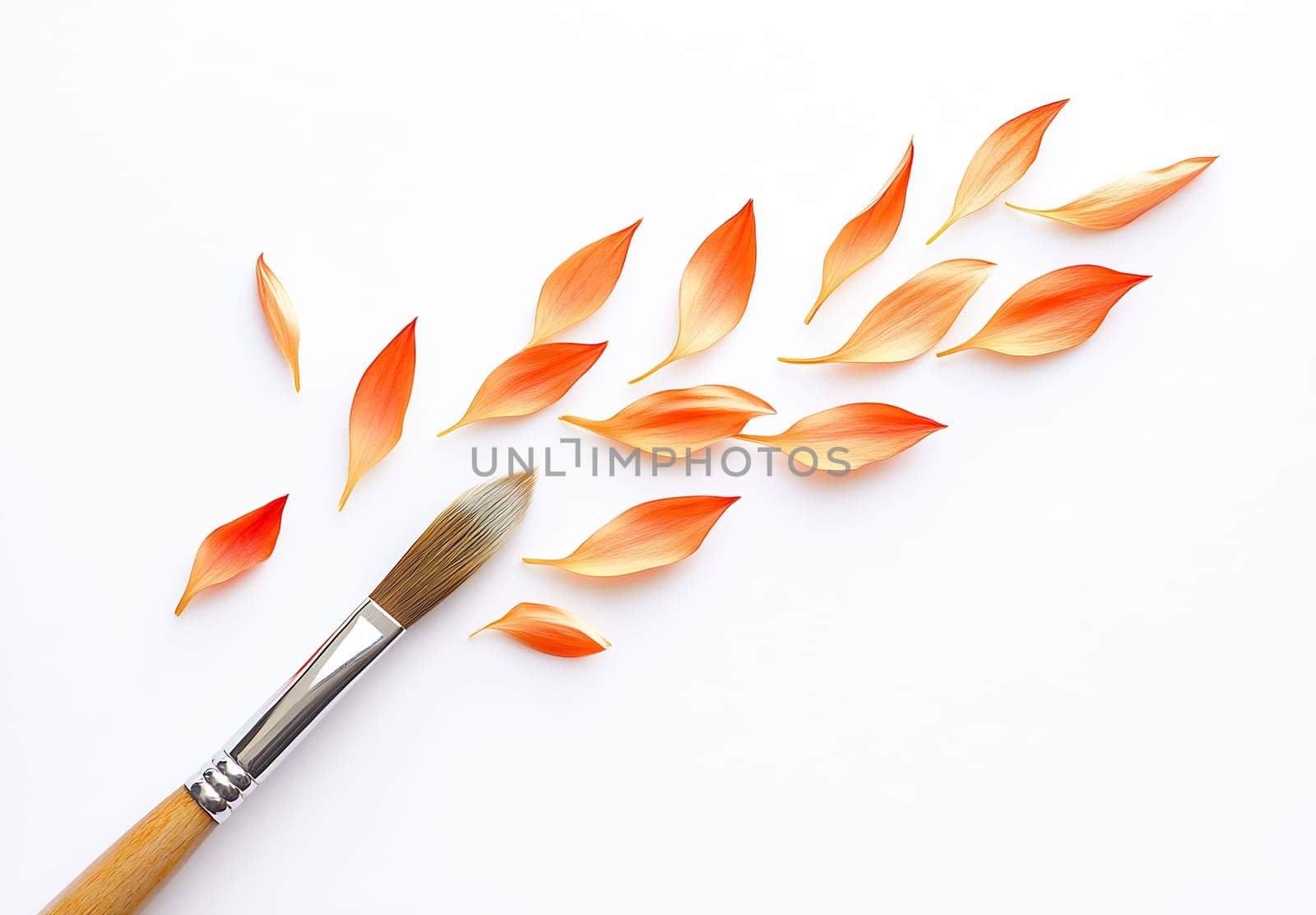 An arrangement of orange petal shapes and a paintbrush on a white background highlights a creative design process in art.