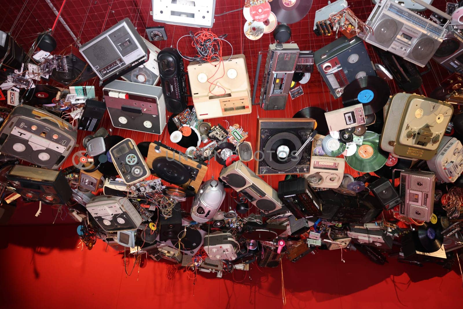 Venice, Italy - May 7 2024: Foreigners Everywhere 60th Venice Art Biennale. John Akomfrah, Listening All Night To The Rain at British Pavilion. Old video and audio players hanging from the ceiling of the red room.