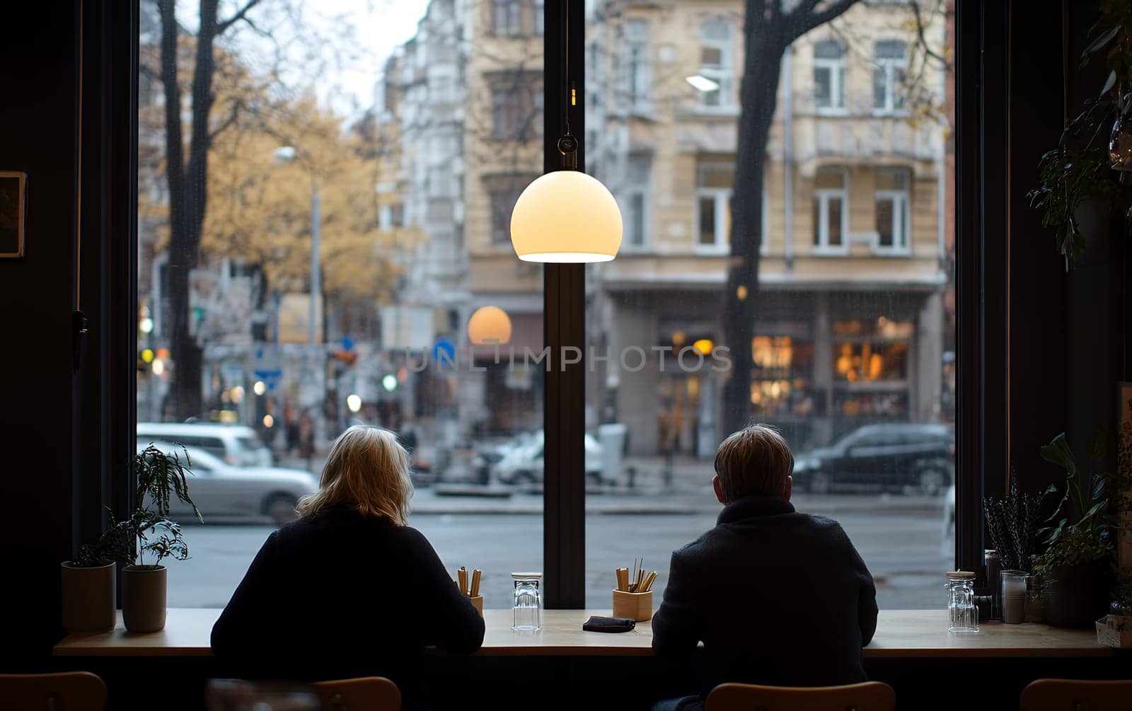 Two people sitting in a modern cafe, observing the lively city life through a large window, with a relaxed atmosphere.