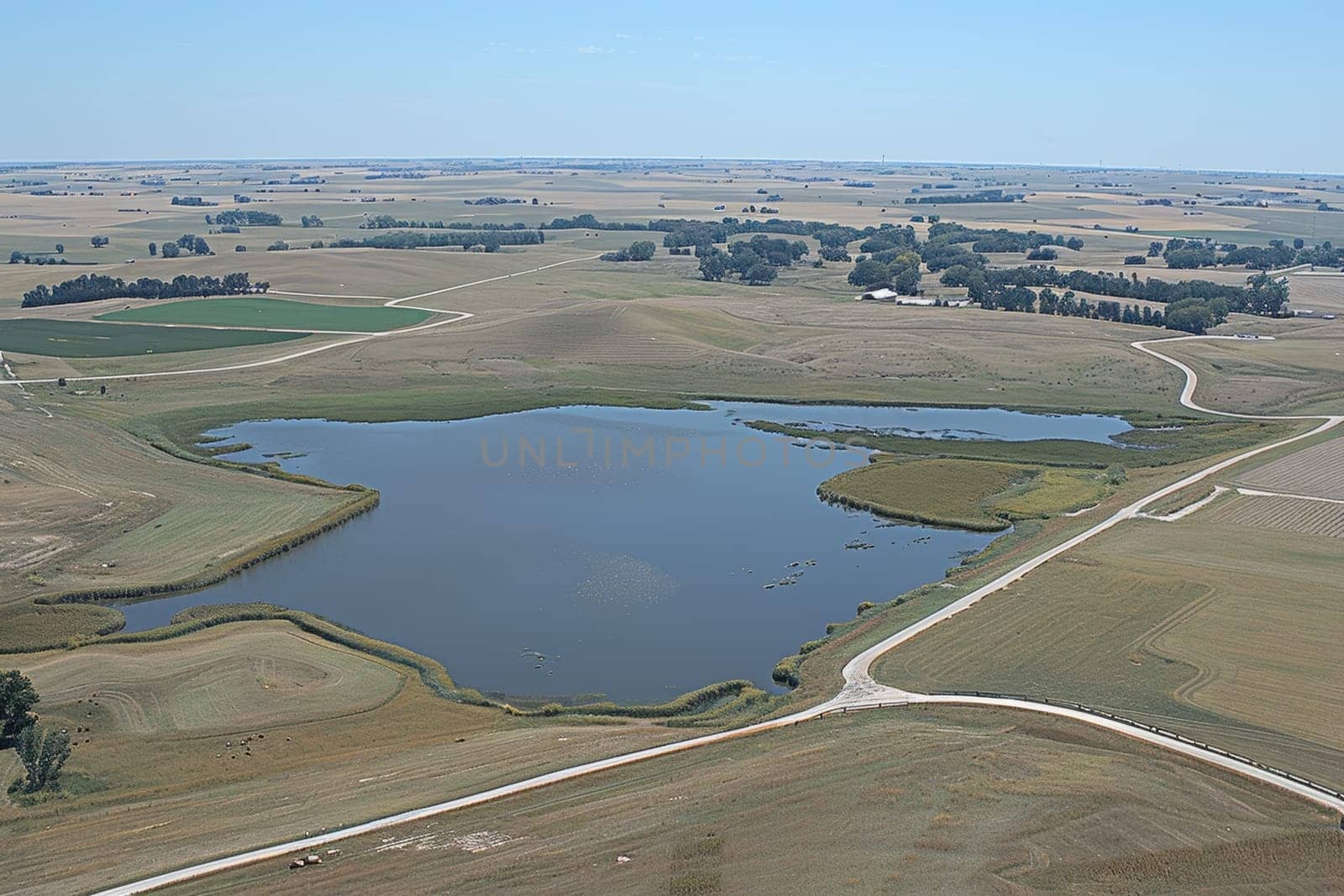 Aerial view of a blue lake surrounded by farmland and prairie, showcasing rural landscape diversity