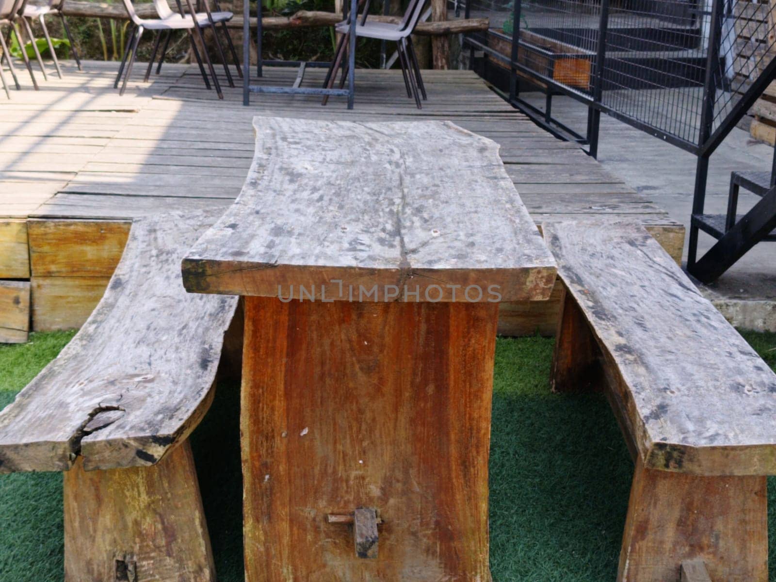 A rustic wooden table and benches set on an outdoor patio, showcasing natural, handcrafted design. Ideal for gatherings, creating a cozy and organic atmosphere.