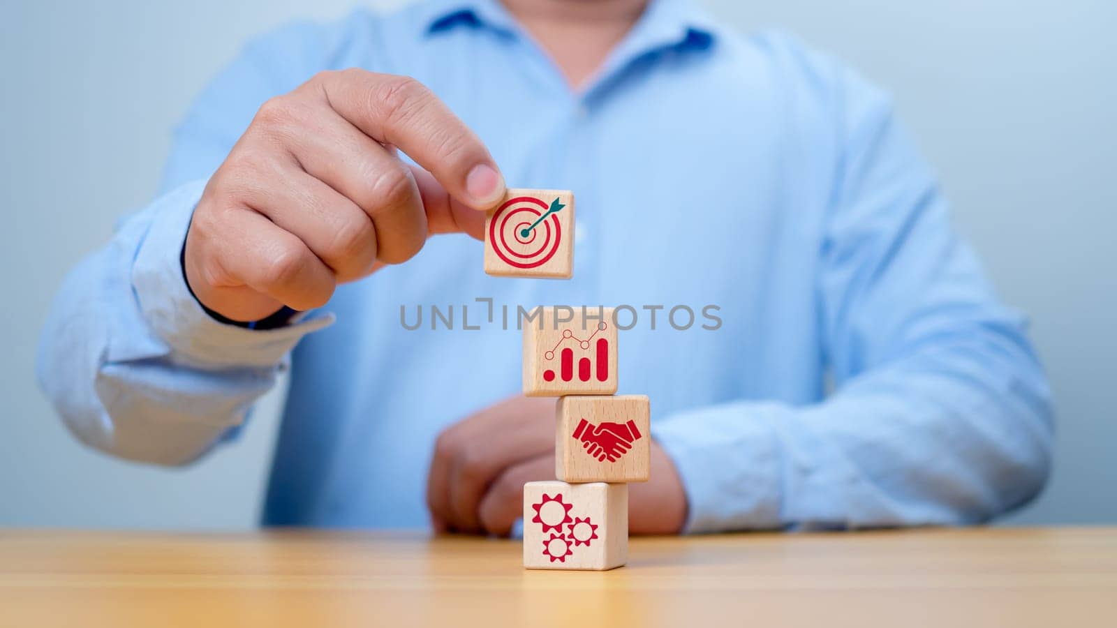 Wood block stacking arranged by a hand, representing a business strategy and Action plan. Targeting the concept of procedure and systematic work approach,Targeting the business concept.