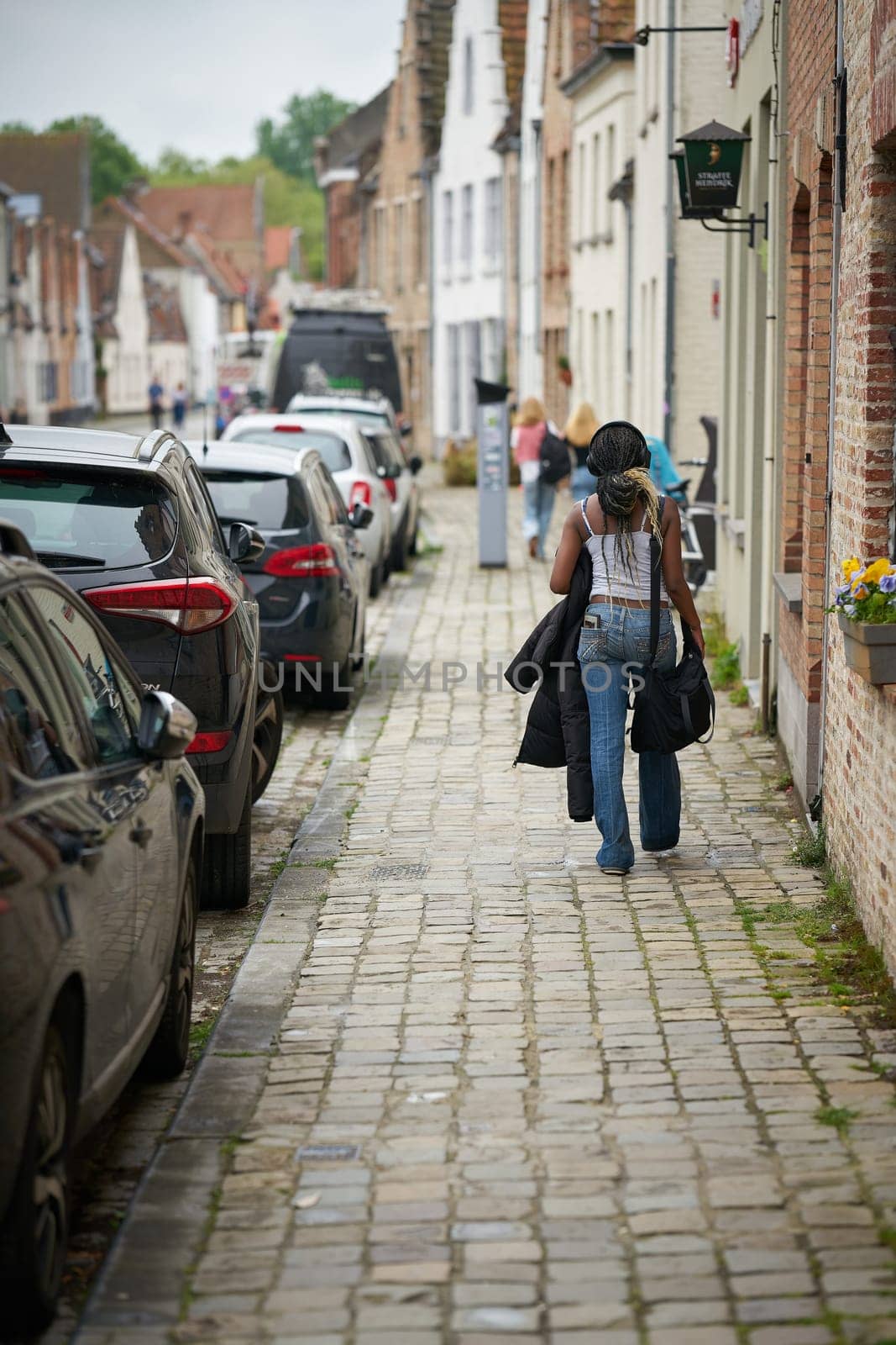 Footpath in the old town of Bruges in Belgium with a young woman of African descent
