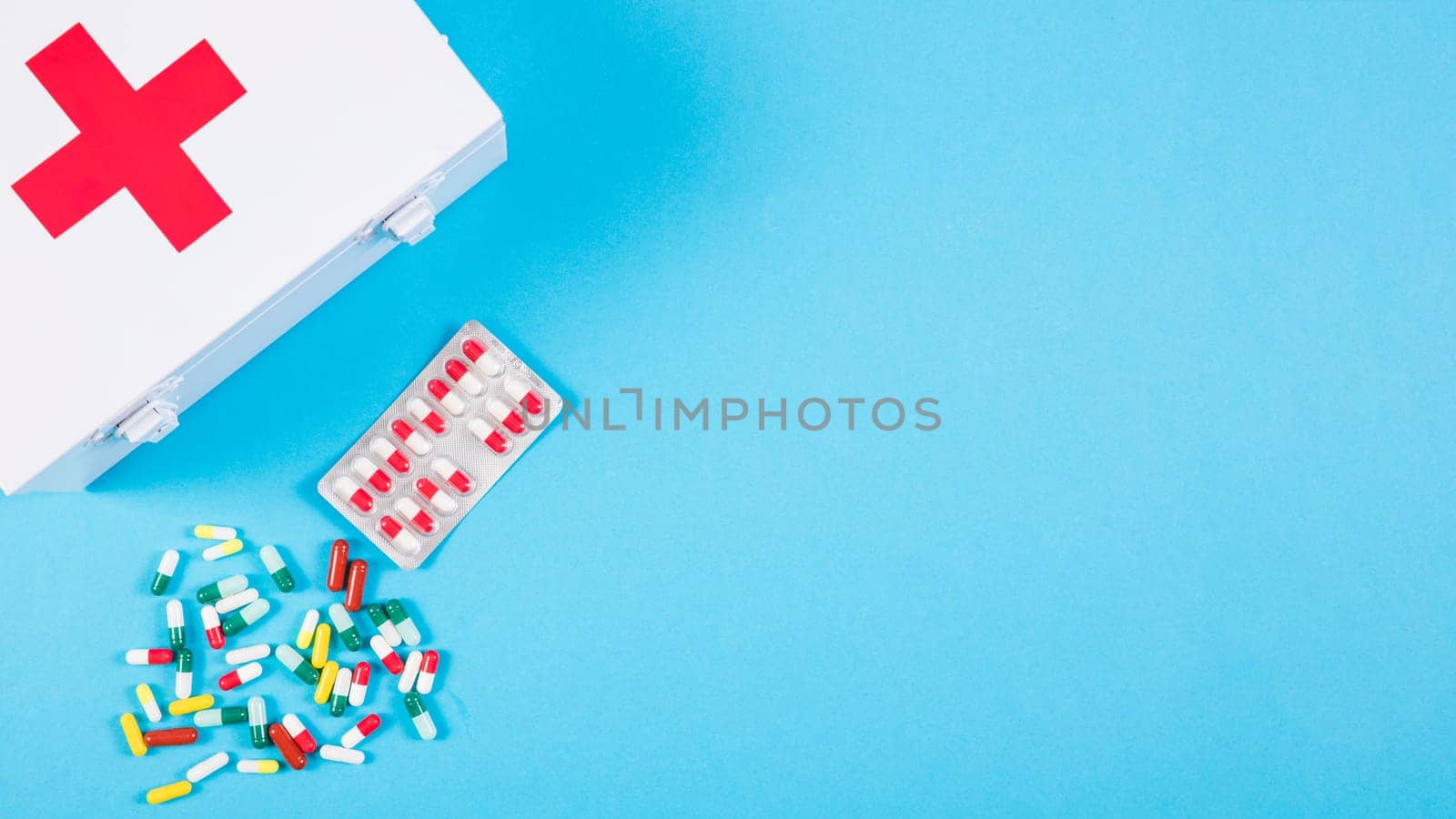 overhead view first aid kit with colorful capsules blue background. High resolution photo