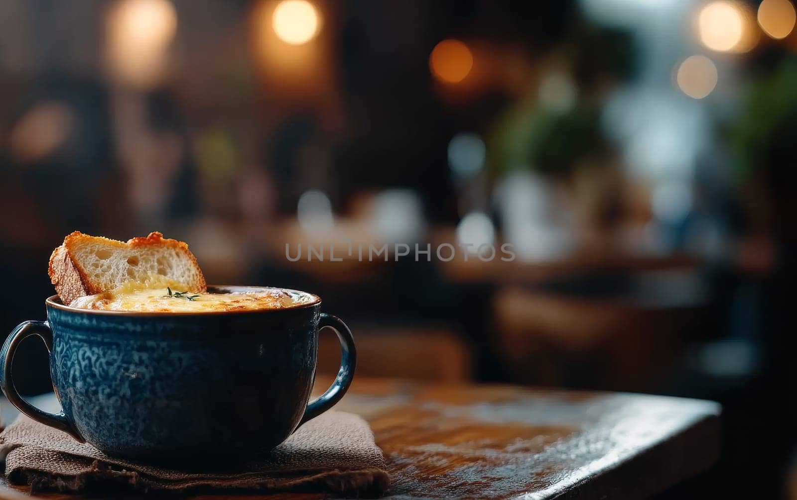 Warm French onion soup topped with melted cheese and bread, served in a cozy, rustic setting.