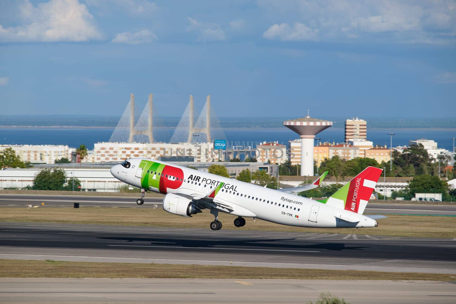 Lisbon, Portugal - September 2, 2023: TAP Air Portugal Airbus A321-251N passenger plane take off in Humberto Delgado Airport in Lisbon with Vasco da Gamma bridge in background