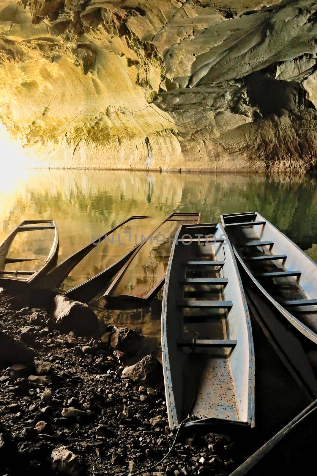 A few long boats, some partly submerged, sunken at the entrance of Kong Lor Cave, a tourist attraction on the Thakhek Motorbike Loop, Laos 2023