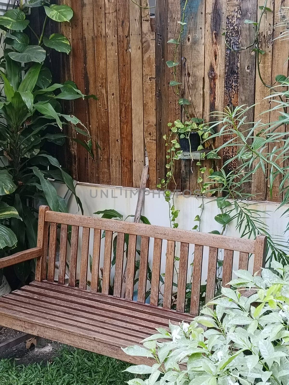 A charming garden area with rustic wooden benches and a table surrounded by lush greenery, creating a peaceful and inviting outdoor space.