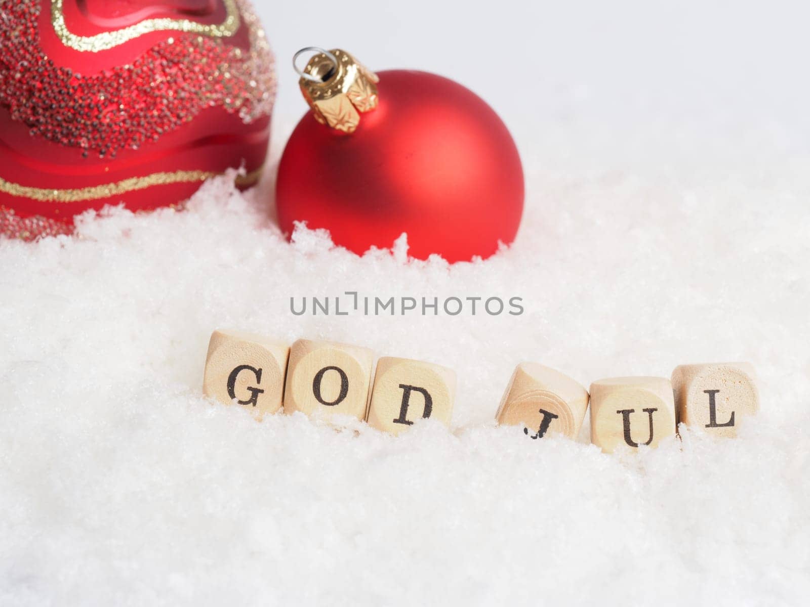 Red Vintage Christmas baubles with wooden blocks and the words God Jul, Scandinavian Merry Christmas in snow