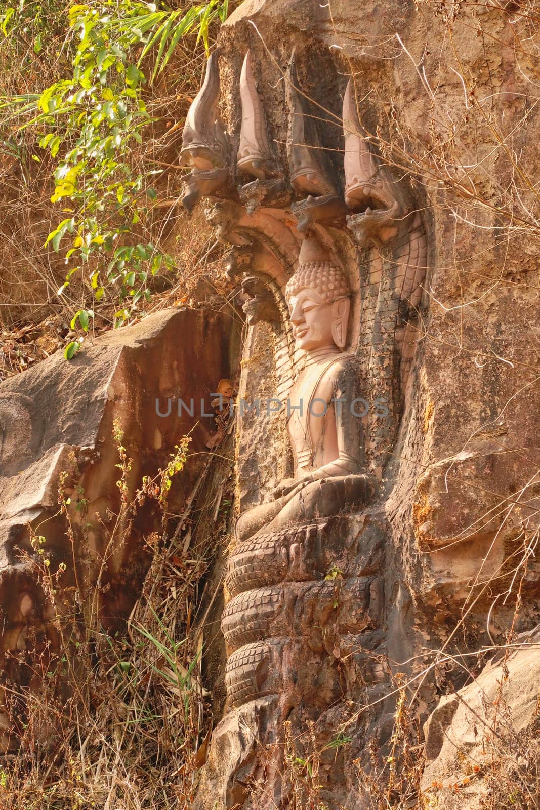 Elaborate Sandstone Buddha Rock Sculpture carved into the rock next to the road on the Thakhek Motorbike Loop, Laos 2023
