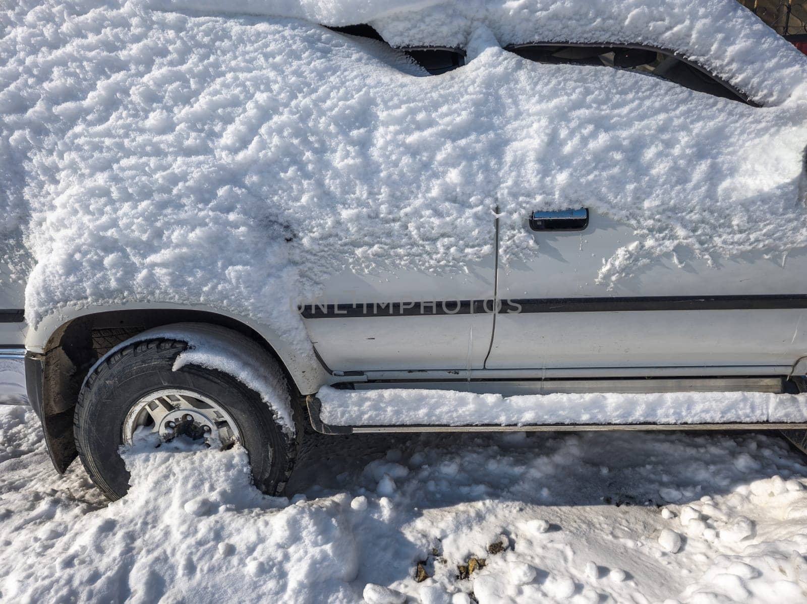 snow covered old white SUV car at sunny white winter day