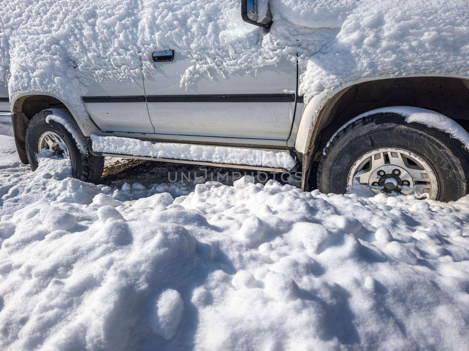 snow covered old white SUV car at sunny white winter day