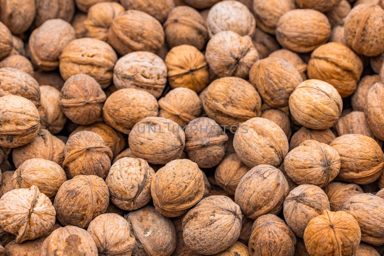 pile of unpeeled walnuts, closeup macro background with selective focus